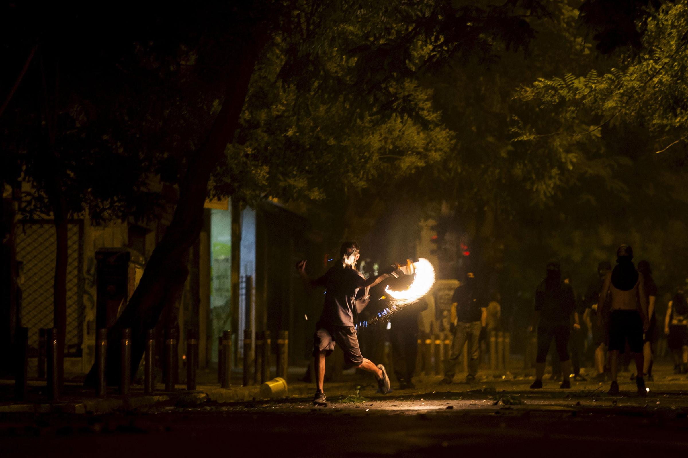 A masked youth throws a petrol bomb at riot police during minor clashes in central Athens, Greece July 5, 2015. Greeks voted overwhelmingly "No" on Sunday in a historic bailout referendum, partial results showed, defying warnings from across Europe that rejecting new austerity terms for fresh financial aid would set their country on a path out of the euro. REUTERS/Marko Djurica
