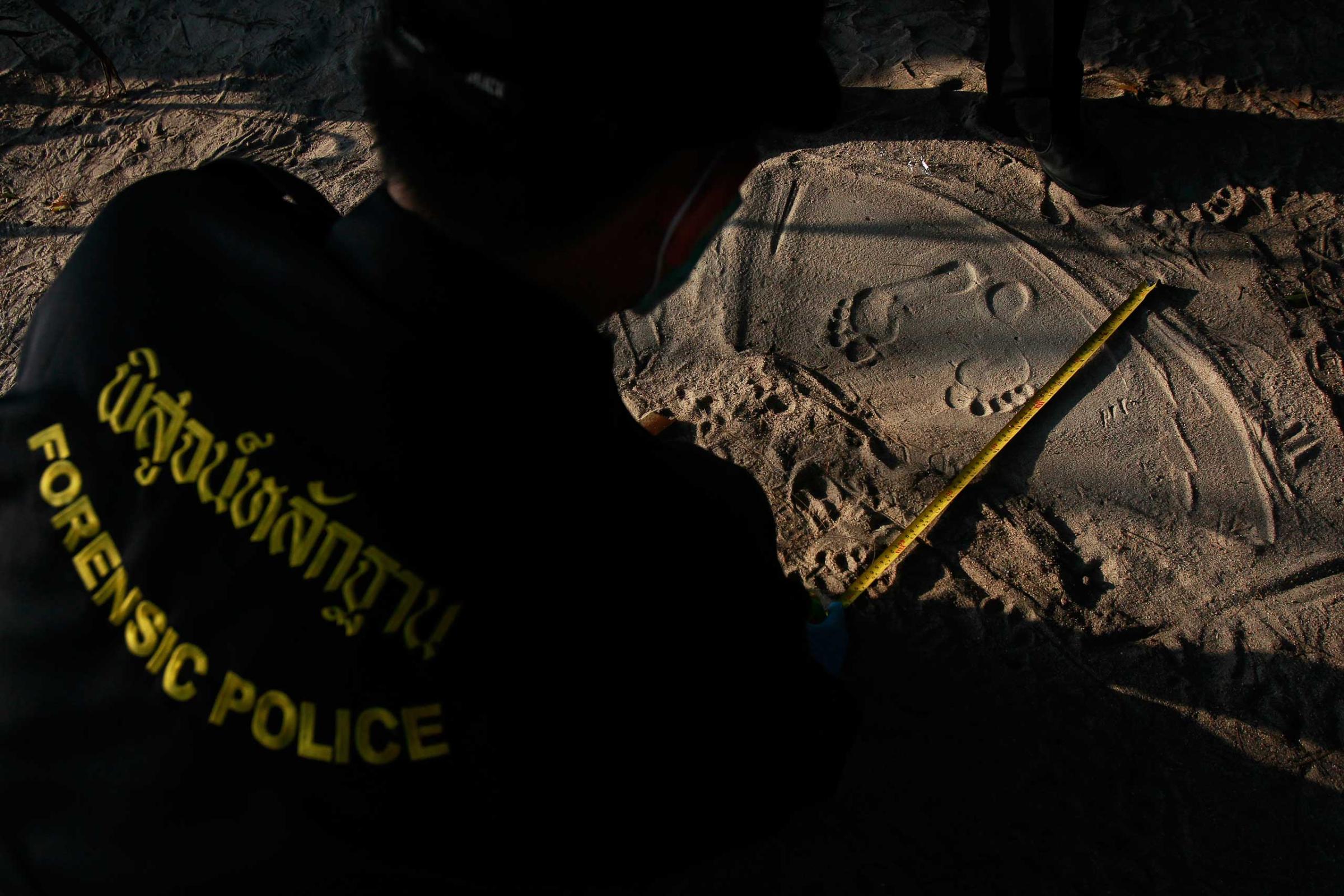 Police measure footprints of a man as data is collected from people who work near the spot where bodies of two killed British tourists were found, on the island of Koh Tao