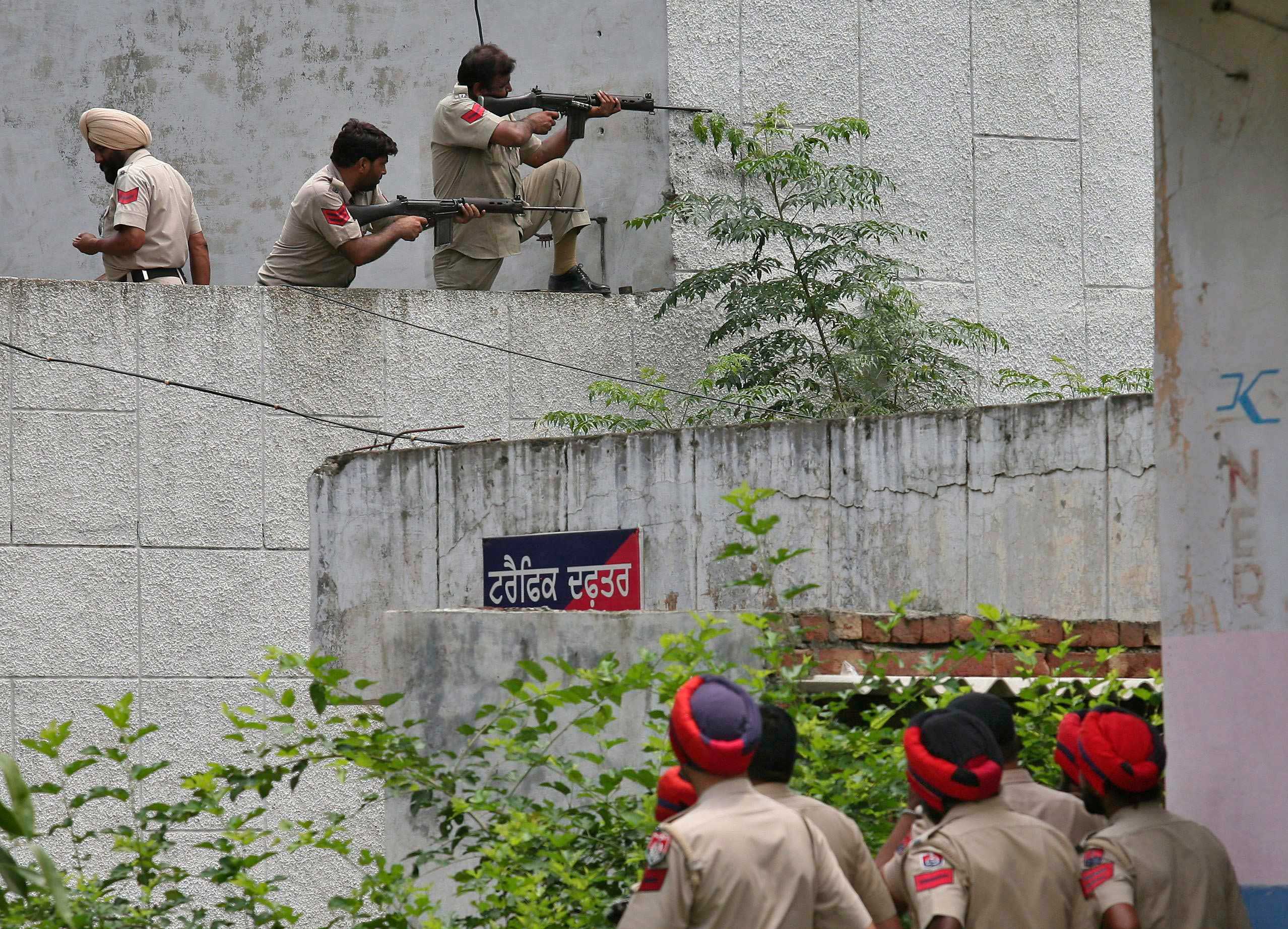 Indian policemen take their positions as their colleagues watch next to a police station during a gunfight at Dinanagar town in Gurdaspur district of Punjab, India on July 27, 2015. (Munish Sharma—Reuters)