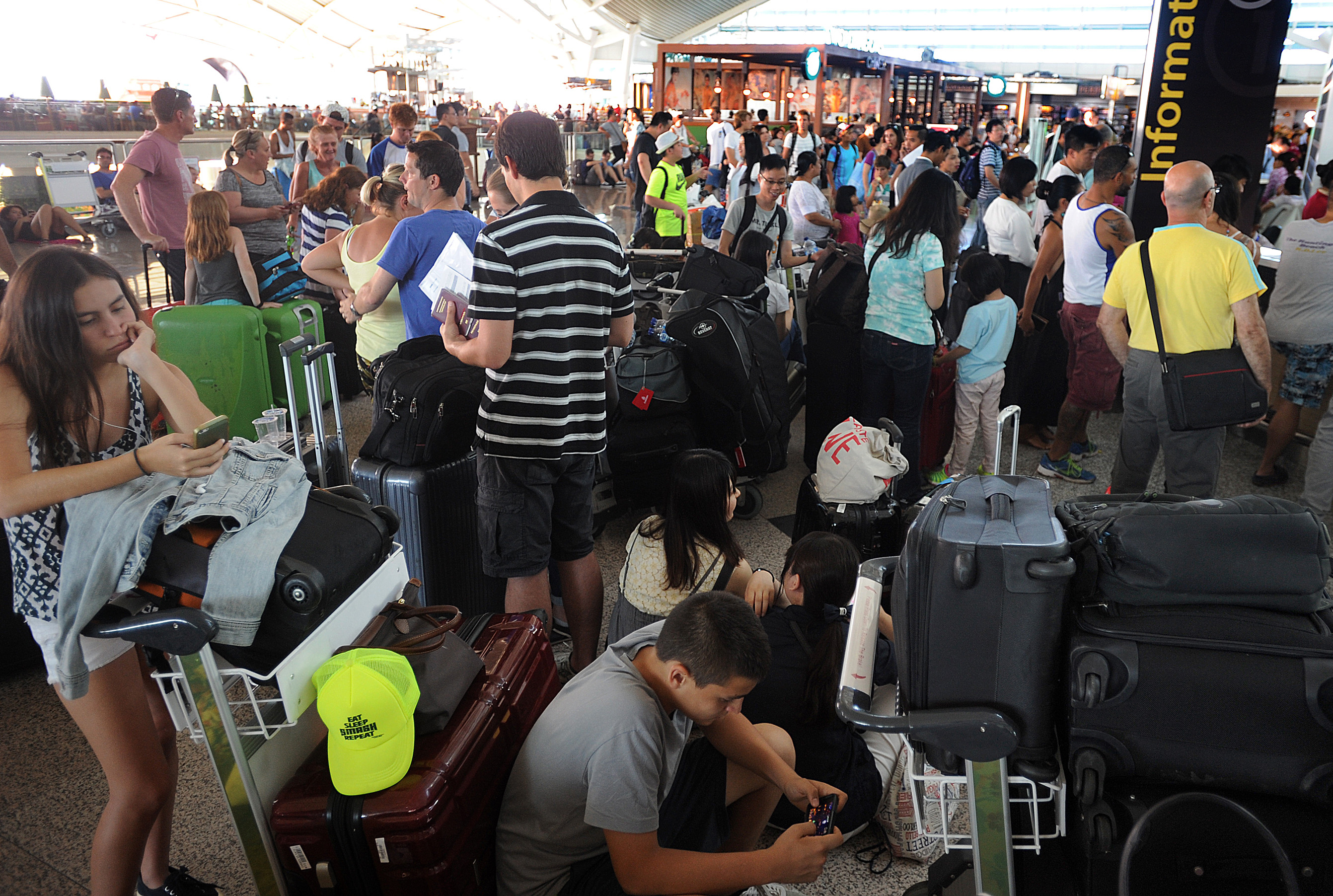 Travelers wait as flights are cancelled due to the eruption of Mount Raung in East Java, at Ngurah Rai International Airport in Bali, Indonesia, Sunday, July 12, 2015.