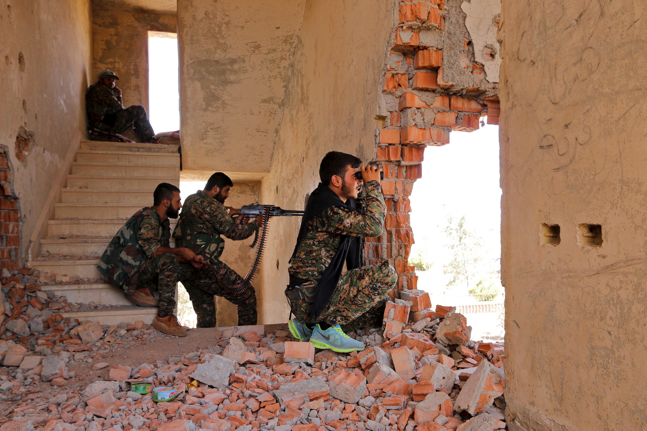 Kurdish People's Protection Units (YPG) fighters take up positions inside a damaged building in al-Vilat al-Homor neighborhood in Hasaka city, as they monitor the movements of Islamic State fighters who are stationed in Ghwayran neighborhood in Hasaka city, Syria on July 22, 2015. (Rodi Said—Reuters)