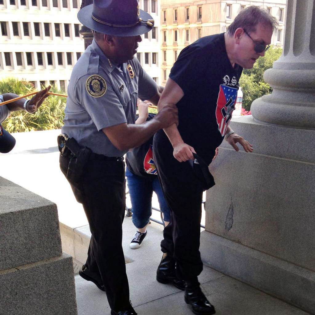 Police officer Leroy Smith helps a man wearing National Socialist Movement attire up the stairs during a rally on July 18, 2015, in Columbia, S.C. (Rob Godfrey—AP)
