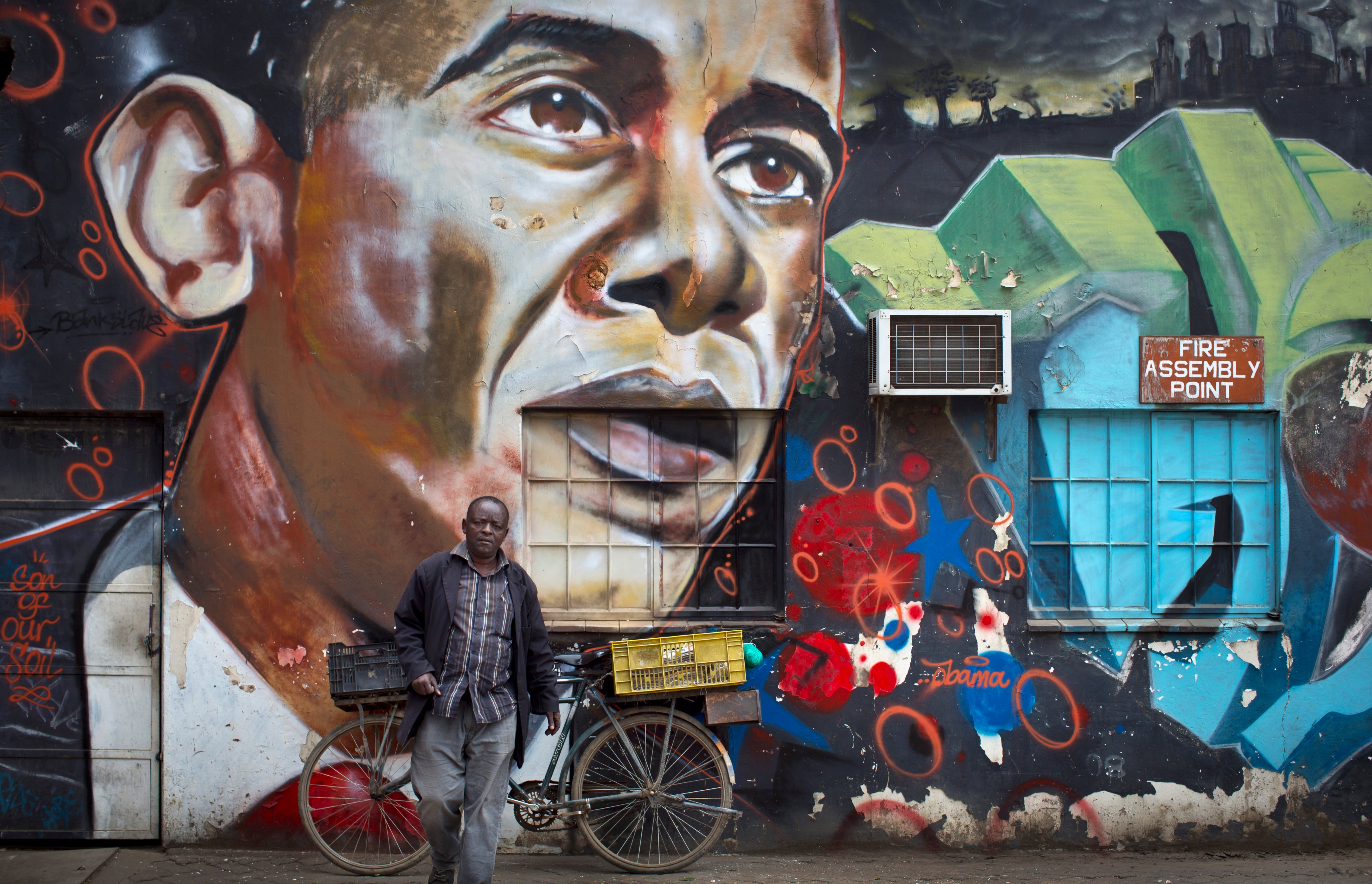 A man walks away after leaning his bicycle against a mural of President Barack Obama, created by the Kenyan graffiti artist Bankslave, at the GoDown Arts Centre in Nairobi on July 22, 2015. (Ben Curtis—AP)
