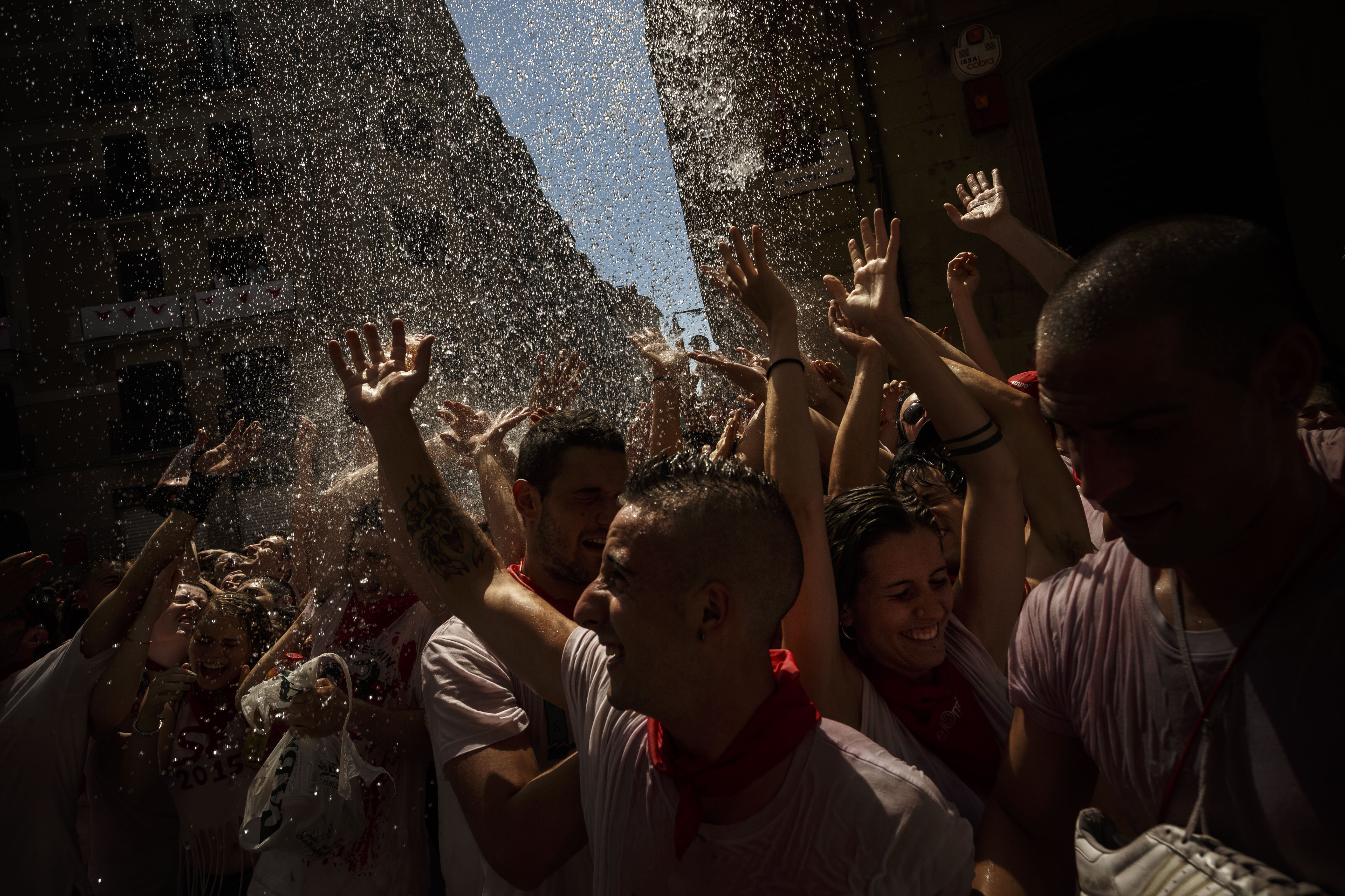 Revelers are sprayed with water as they celebrate during the launch of the 'Chupinazo' rocket, to celebrate the official opening of the 2015 San Fermin fiestas in Pamplona, Spain on July 6, 2015.