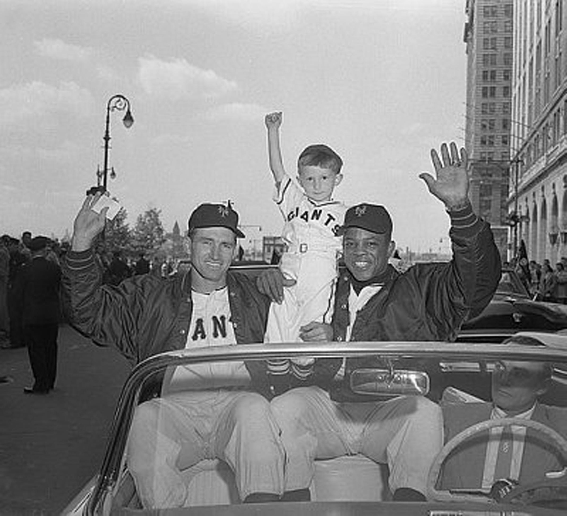 Four year old Kevin Currey made an appearance at today's parade for the N.L. Champions, all decked out in a Giant uniform cut to size. He caught the eye of Alvin Dark and Willie Mays and they scooped him up into their car during the big parade. A big day, indeed for Kevin and the champs. September 1954