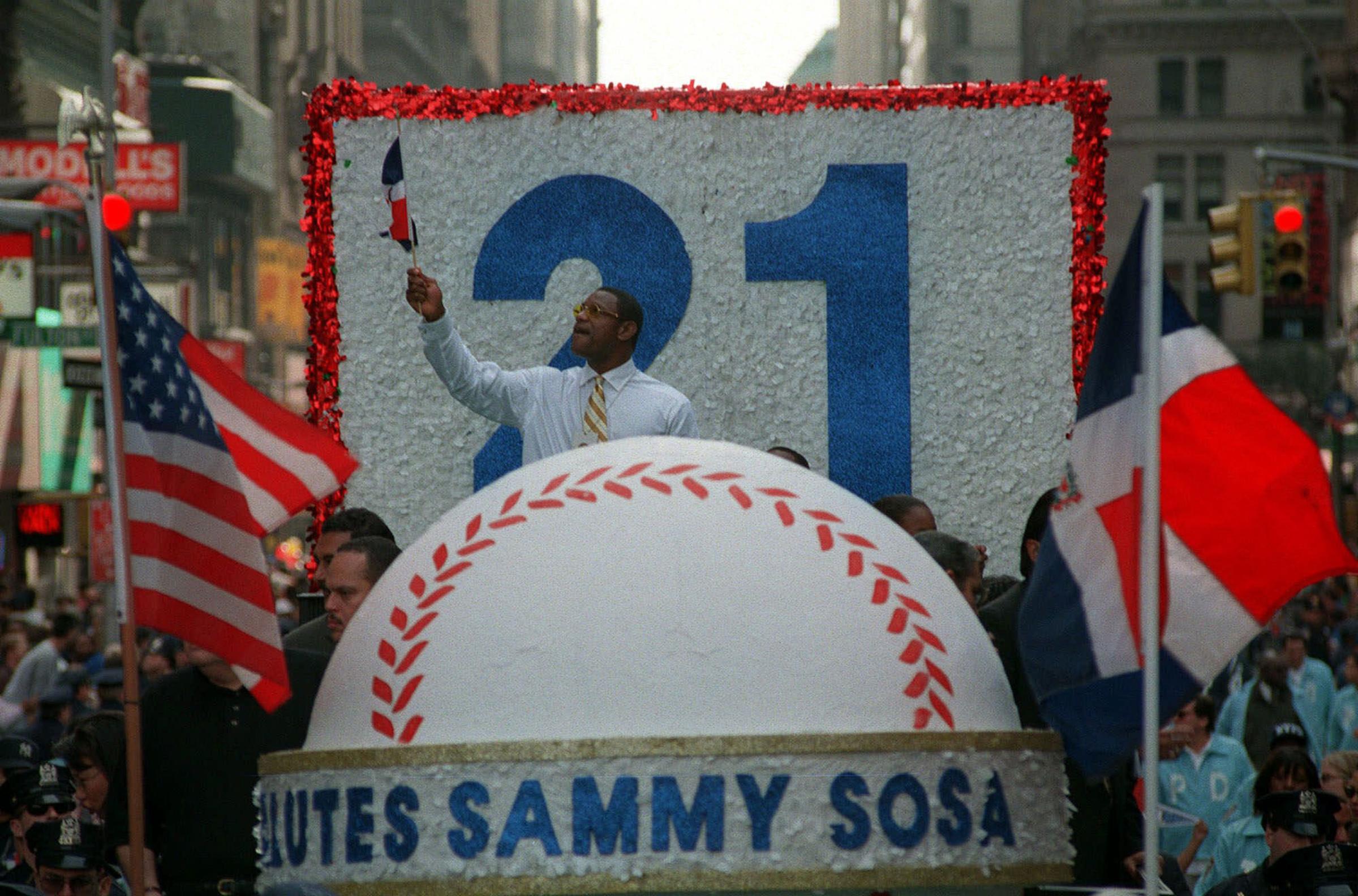 SChicago Cubs' Sammy Sosa gestures from a float, between flags from the United States and the Dominican Republic, during a parade in his honor in New York Saturday Oct. 17, 1998. SA