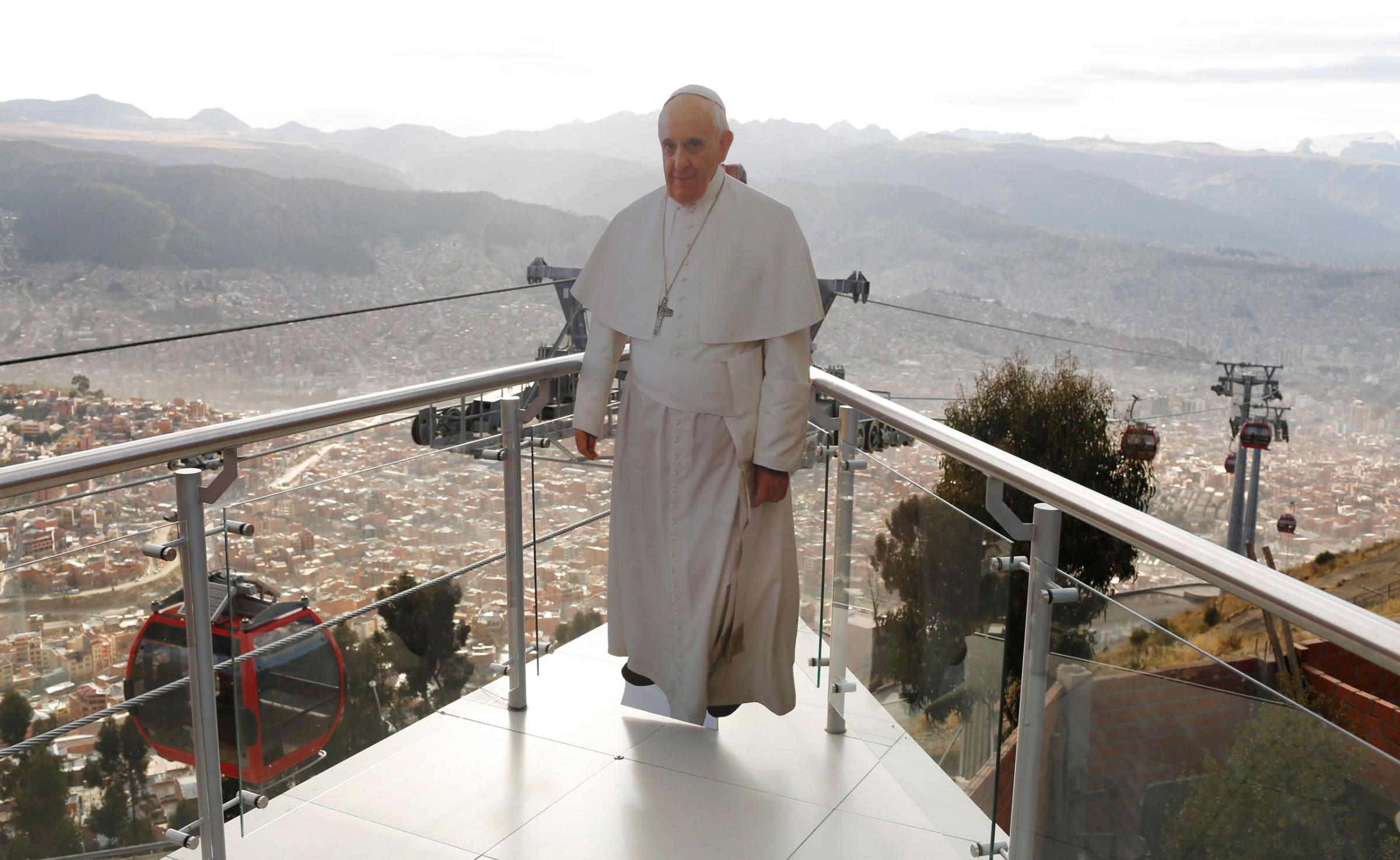 In this July 3, 2015 photo, a life-size cutout image of Pope Francis stands over La Paz, seen from the cable car platform in El Alto, placed there by the transportation workers for commuters to pose with for photos, part of the city's promotion of the pope's upcoming visit to Bolivia. The pope's trip to South America that includes Bolivia is set for July 5-12, though he will only spend four hours in Bolivia's capital due to the altitude, church officials say. (AP Photo/Juan Karita)