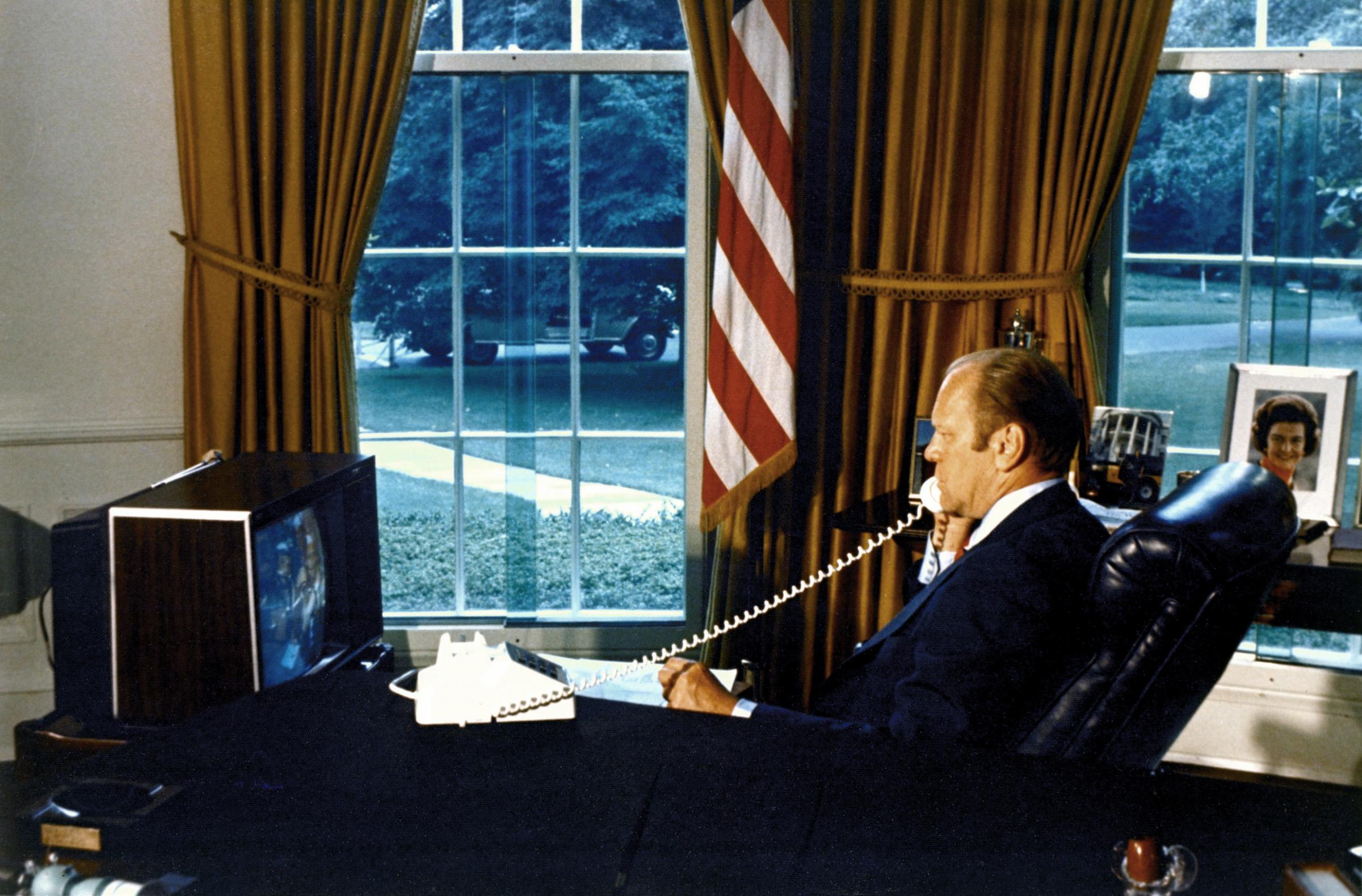 President Gerald R. Ford watches crewmen Tom Stafford, Donald Slayton and Valeriy Kubasov on a television as he talks to them by phone while they orbited the Earth on July 18, 1975. The American Apollo spacecraft and Soviet Soyuz spacecraft were docked.