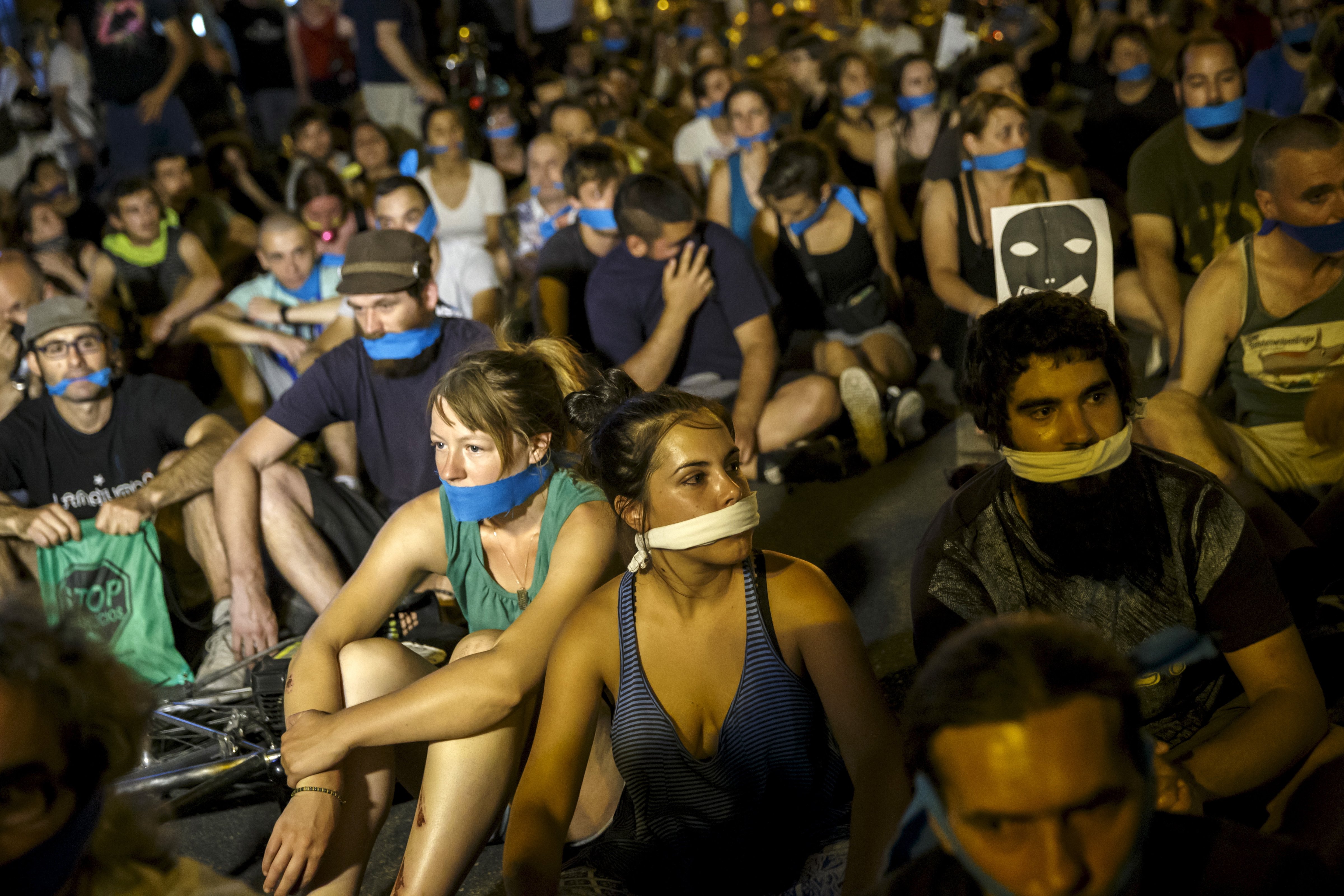 Demonstrators with their mouths taped sit outside the Spanish parliament during a protest against Spanish government's new security law in central Madrid