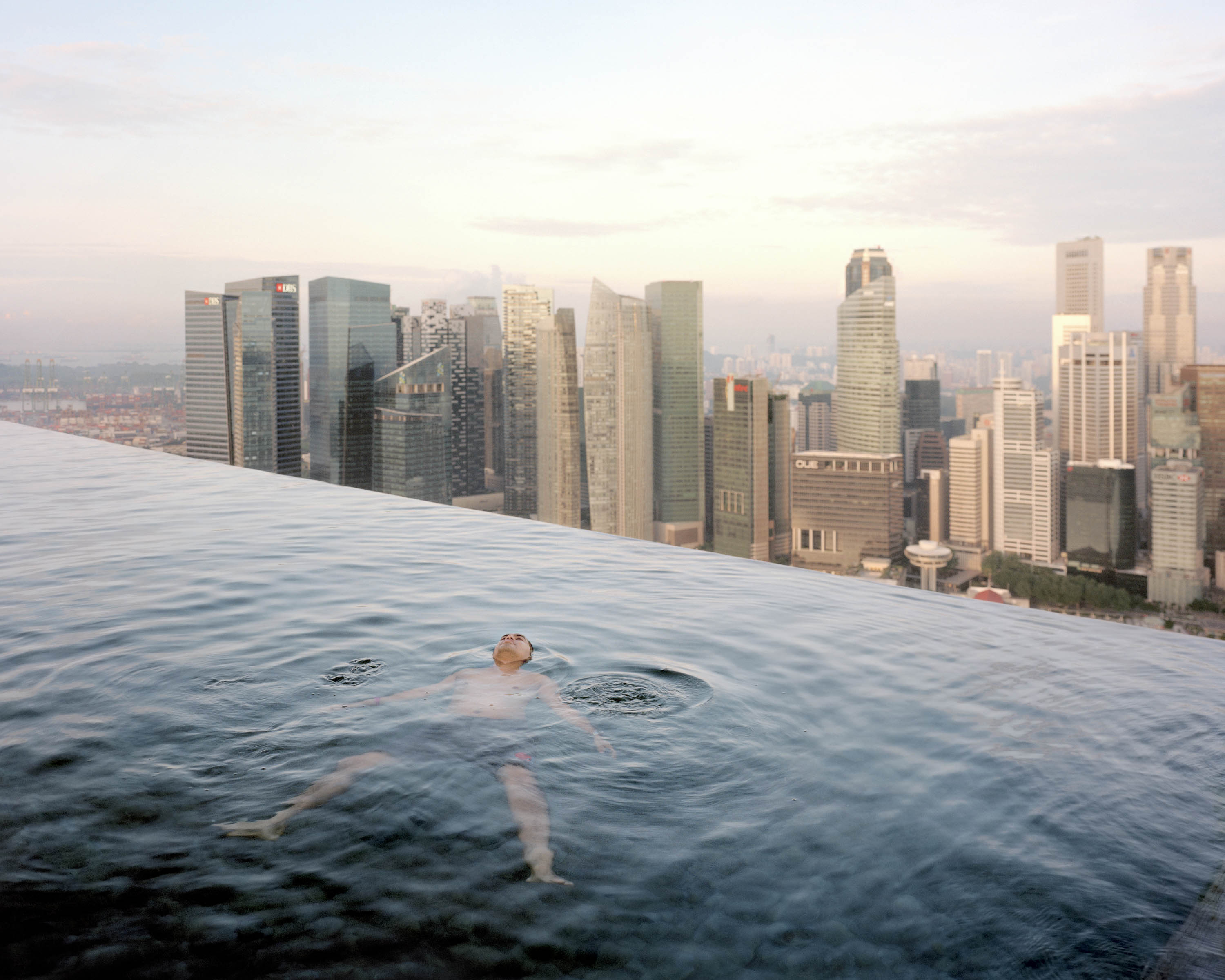 A man floats in the infinity pool on the 57th floor of the Marina Bay Sands Hotel, overlooking Singapore’s financial district. (Paolo Woods &amp; Gabriele Galimberti—Institute)