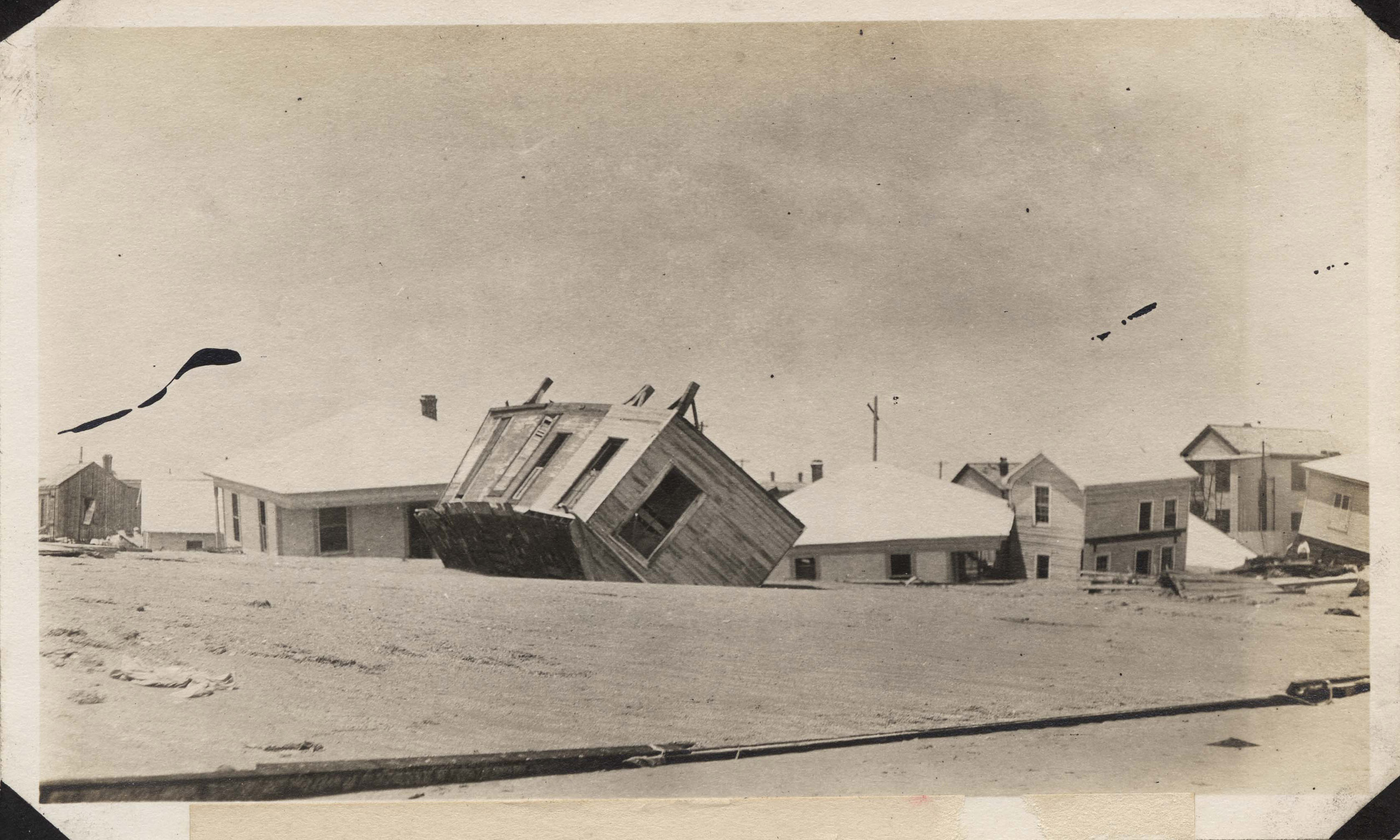 Wrecked houses submerged in sand on the east end of Galveston on Seawall Boulevard. One house has been turned upside down by the hurricane.