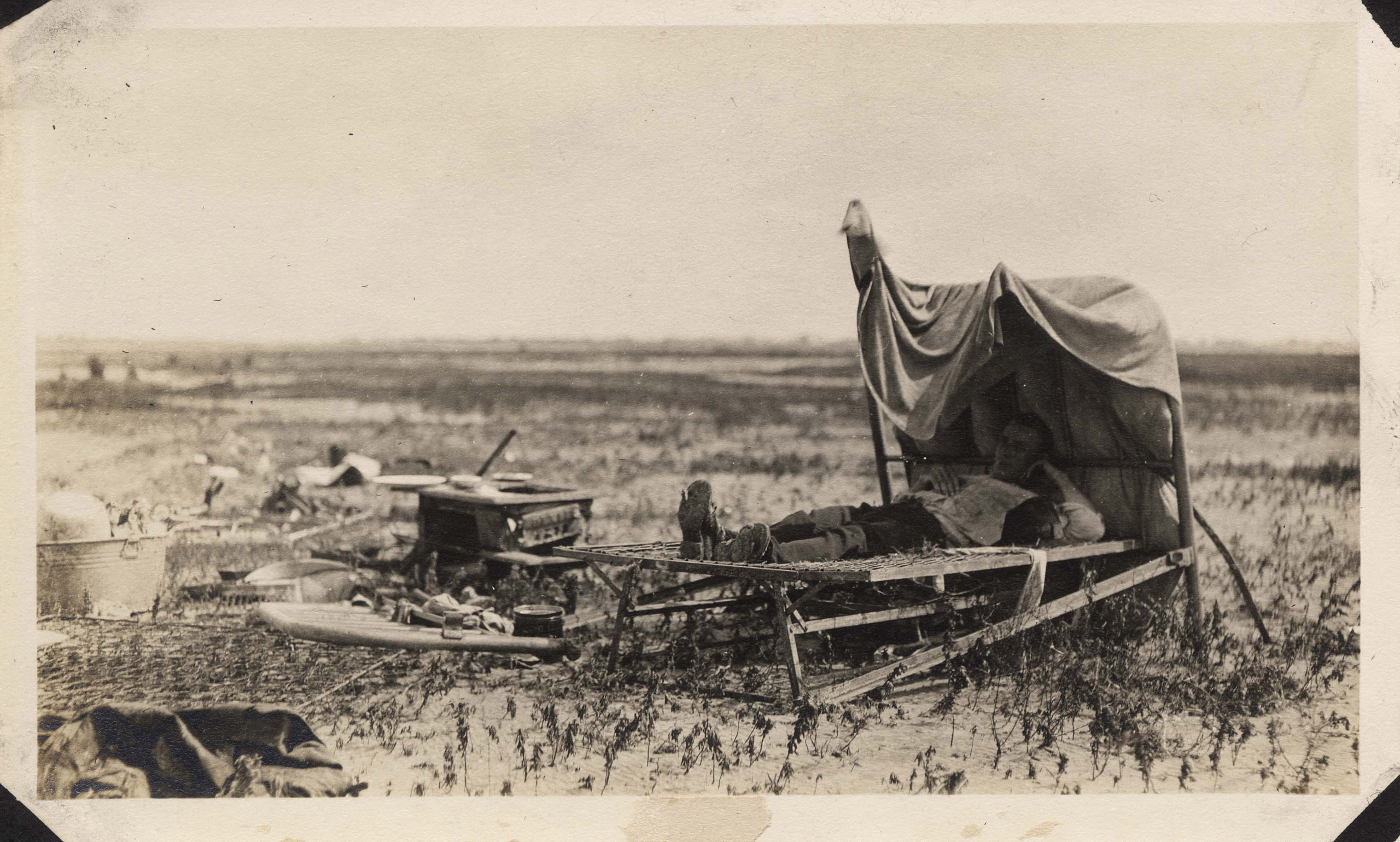 A man lies in a cot, surrounded by the debris from his former home.