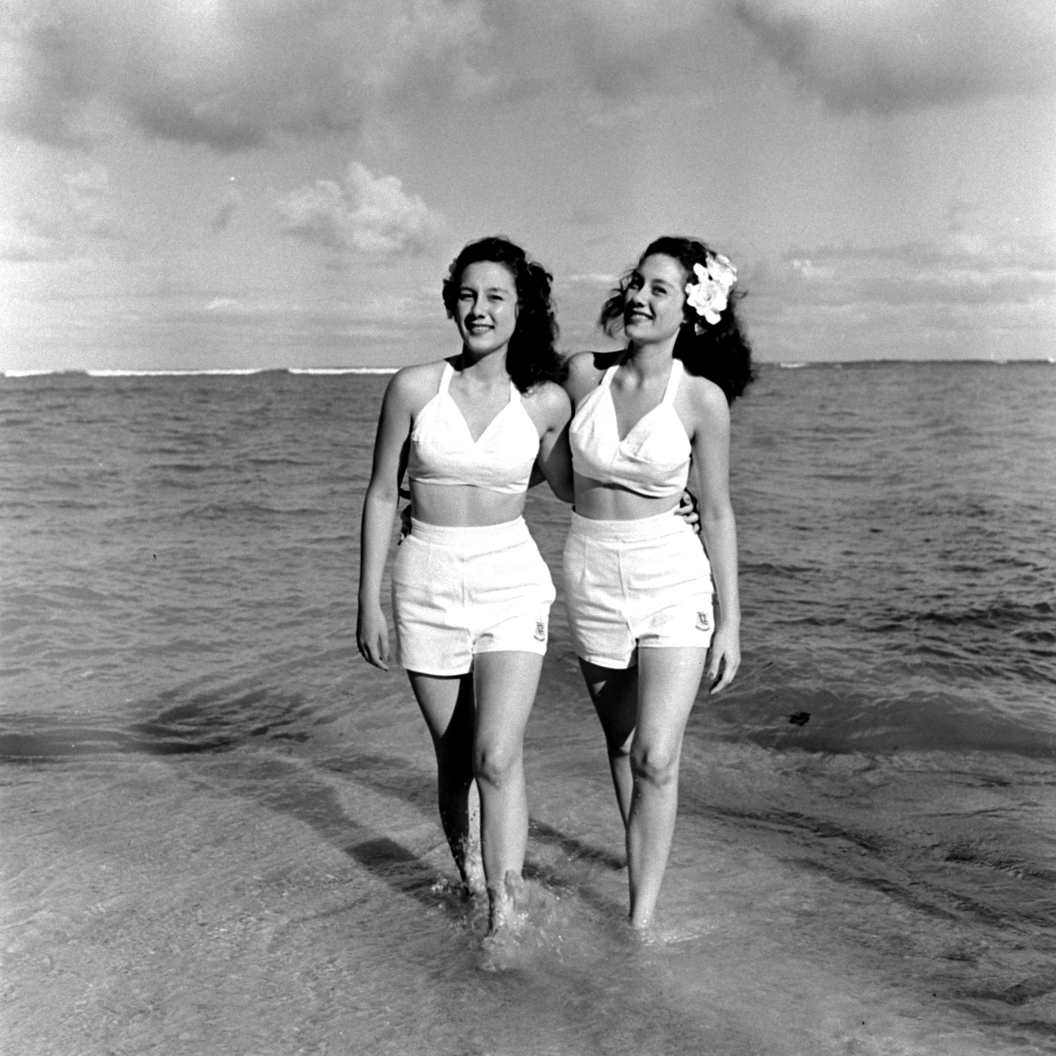 Two Hawaiian girls walking along the shore.