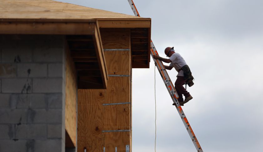 A construction worker climbs on the roof of a home. (Joe Raedle—Getty Images)
