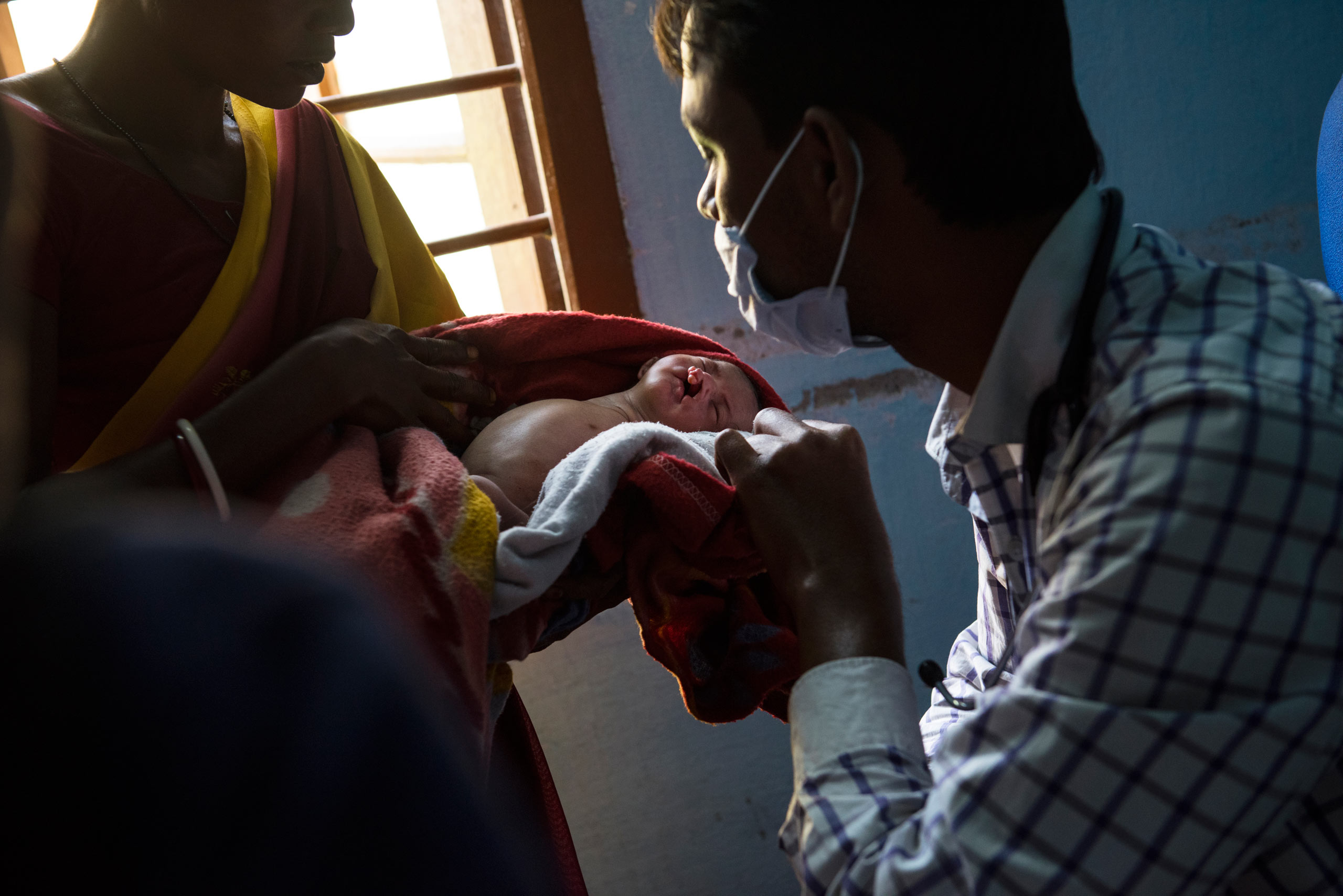 Sosana Gowala holds up her severely deformed nephew for the doctor to see, in the Dhekiajuli Community Health Center, hours after her niece, Resonate Bhumi gave birth to a baby with no arms and a cleft palate in the village of Holing Kata, in the Tinkharia plantation, Assam, India. April 8, 2015.