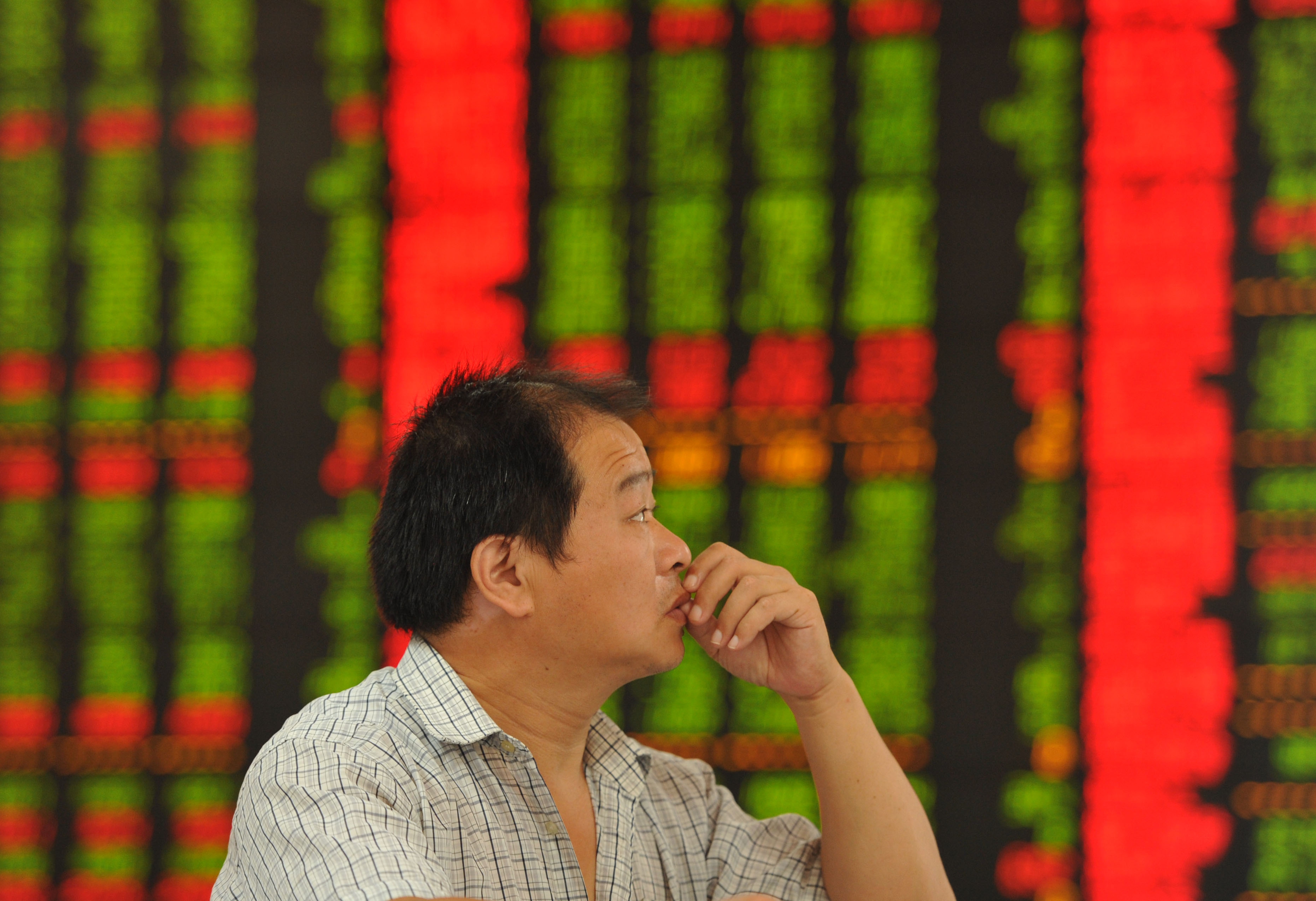 A concerned Chinese investor looks at prices of shares (red for price rising and green for price falling) at a Chinese stock brokerage house on August 5, 2015. (An xin—Imagechina/AP)