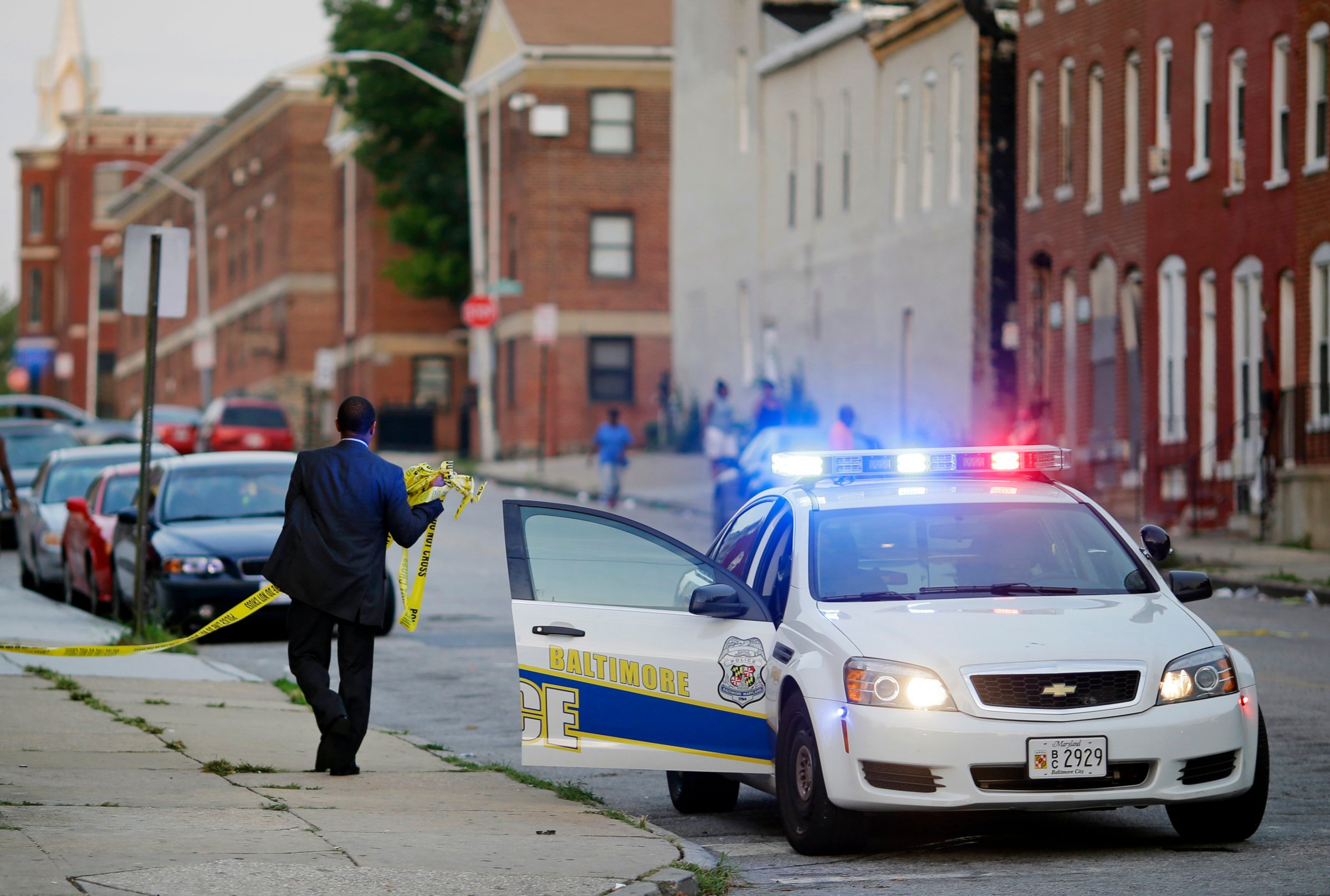 A member of the Baltimore Police Department removes crime scene tape from a corner where a victim of a shooting was discovered in Baltimore on July 30, 2015.