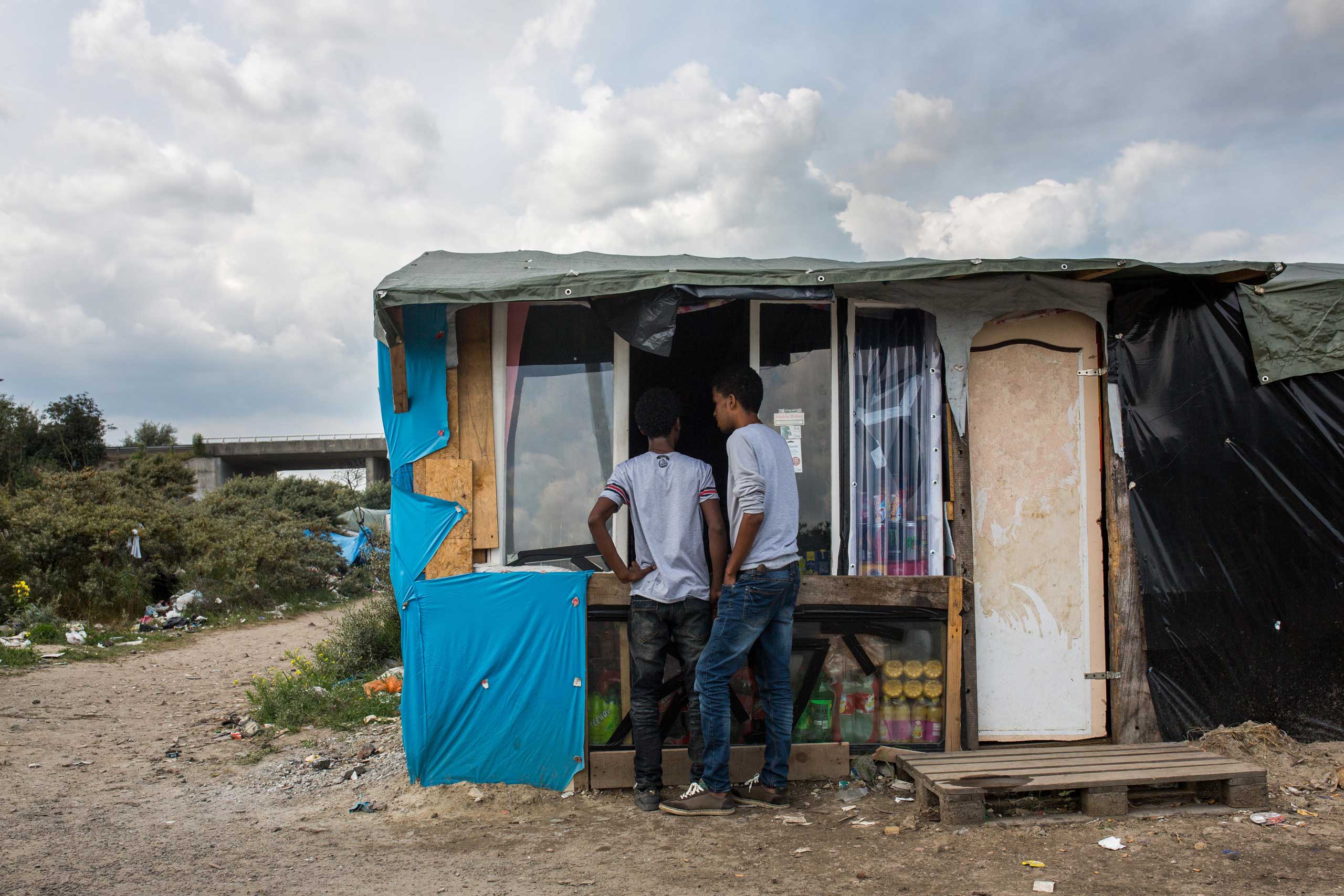 Men buy from a shop run by Afghans at a make shift camp near the port of Calais in Calais, France, on July 31, 2015. (Rob Stothard—Getty Images)