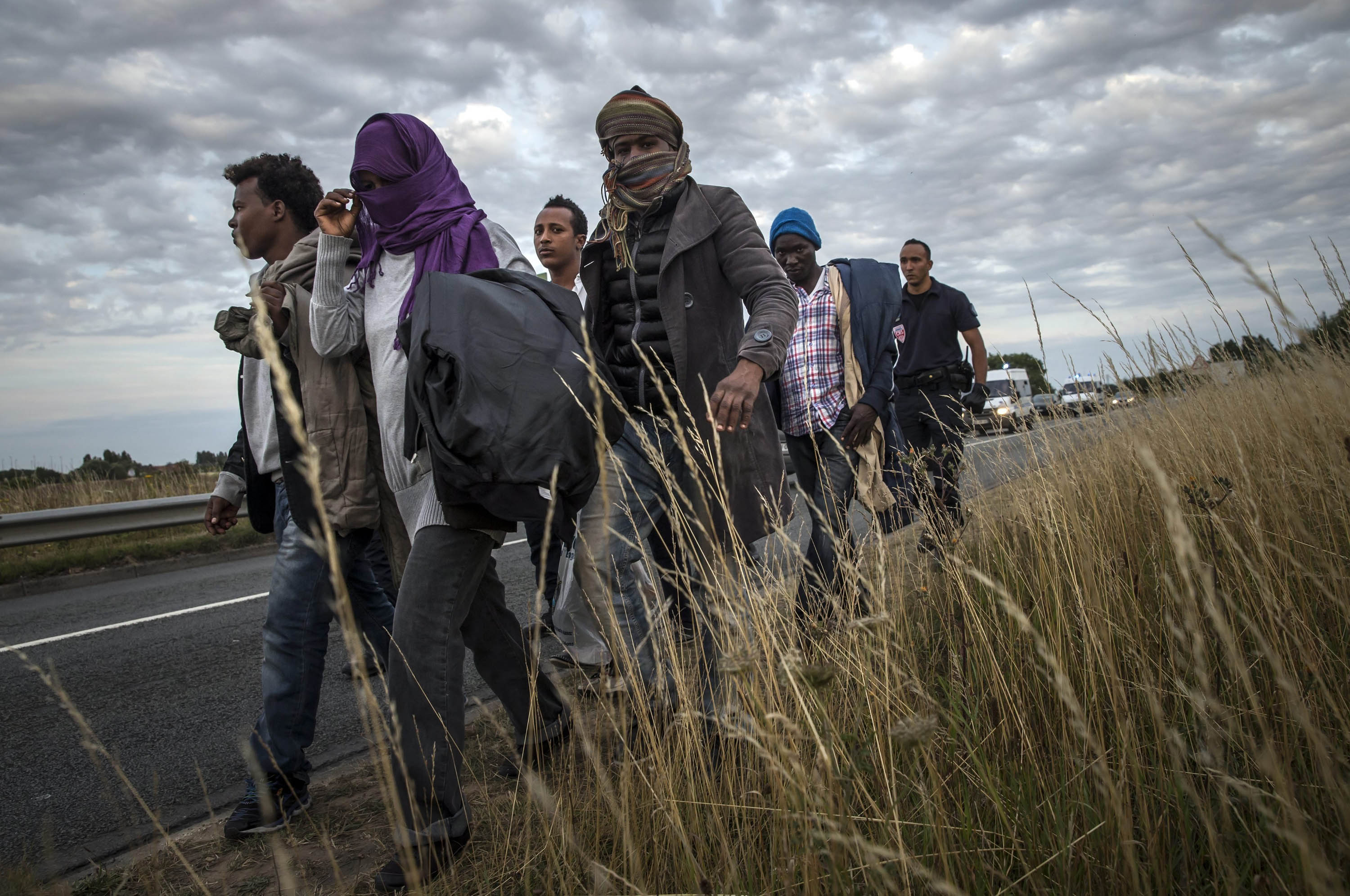 French police officers escort Eritrean migrants away from the Channel Tunnel entrance on Aug. 3. (Etienne Laurent—EPA)