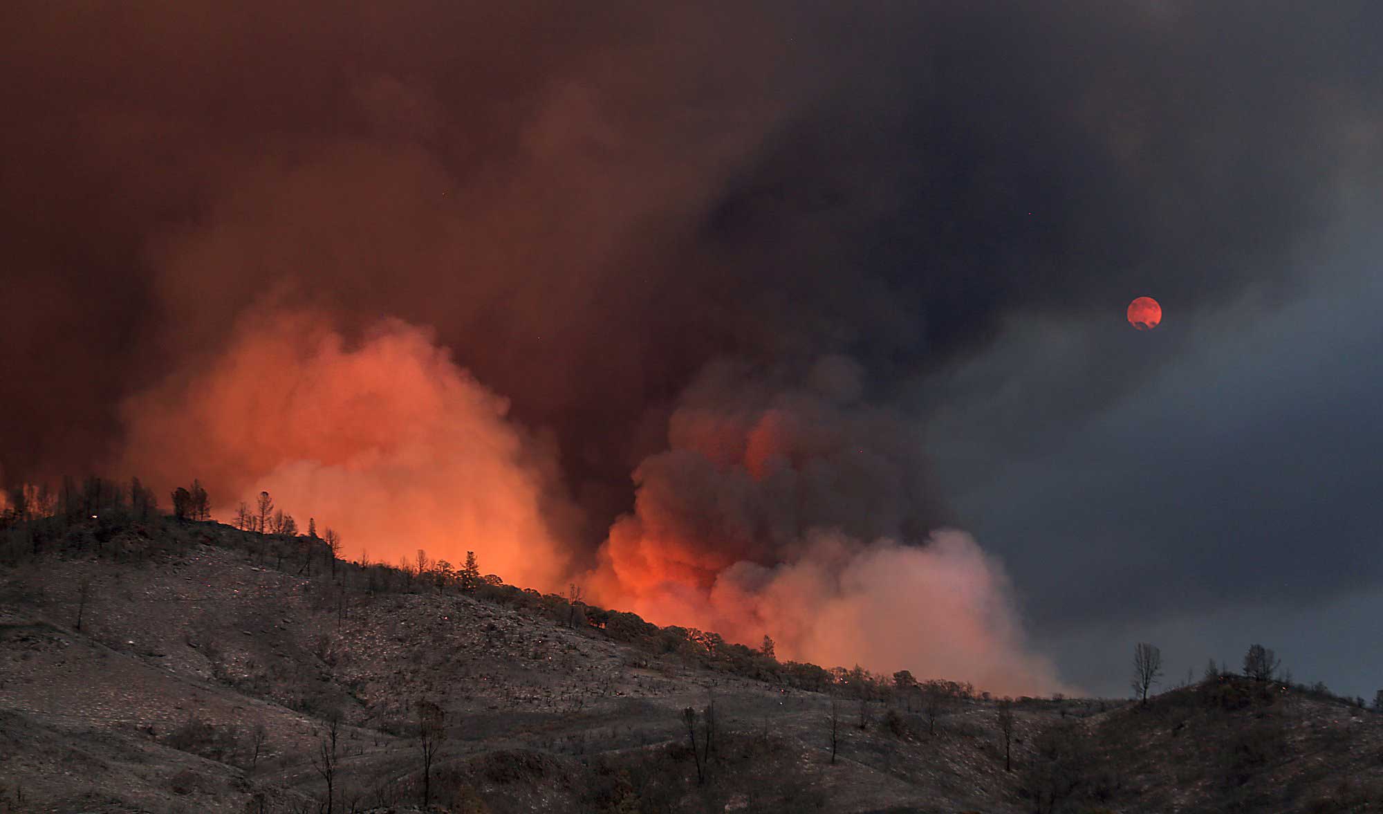 Fire blazes as smoke tints the view of the moon rising over the Rocky Fire near Lower Lake, Calif on July 30, 2015.