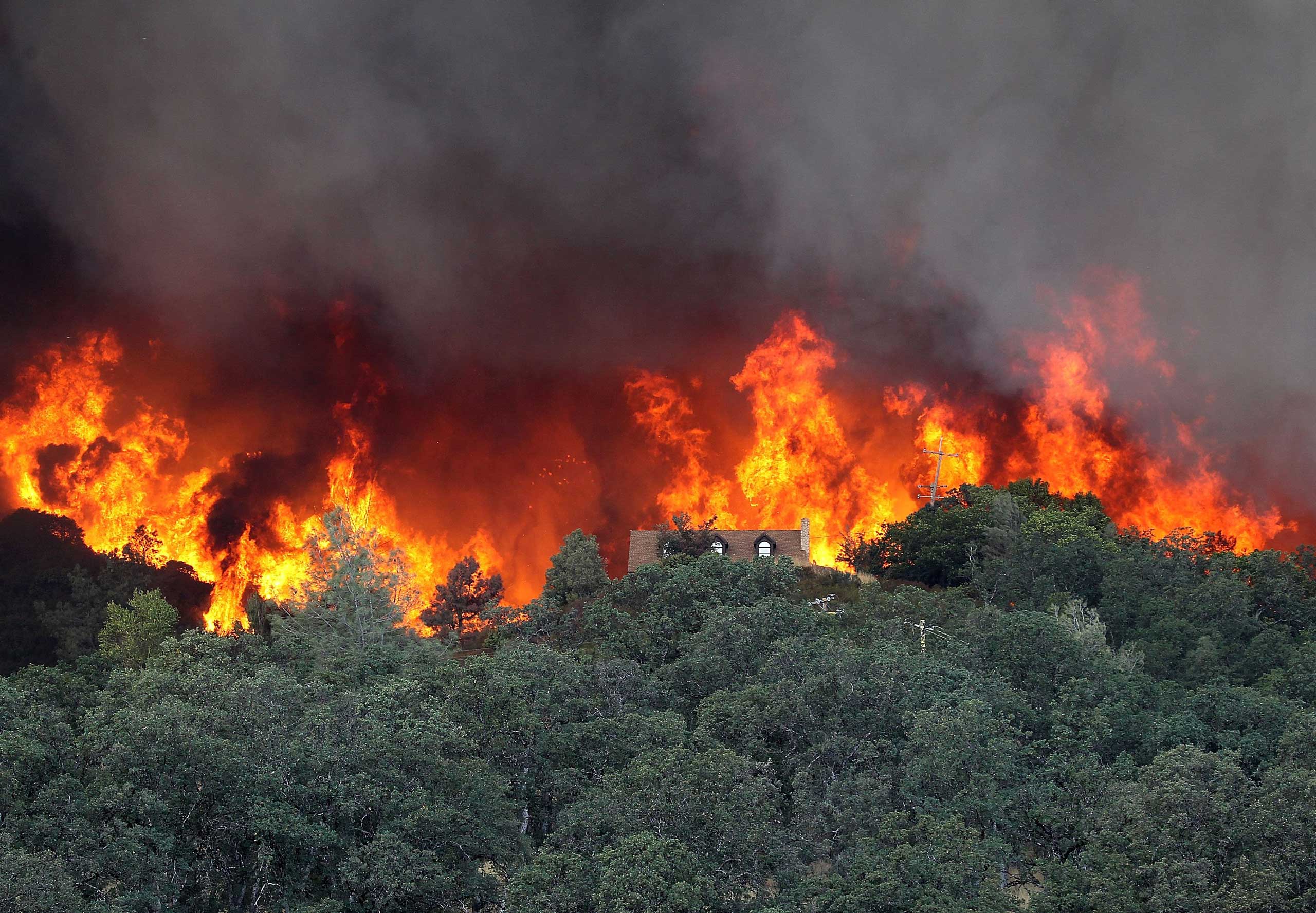 Flames from the Rocky Fire approach a house in Lower Lake, Calif. on July 31, 2015.