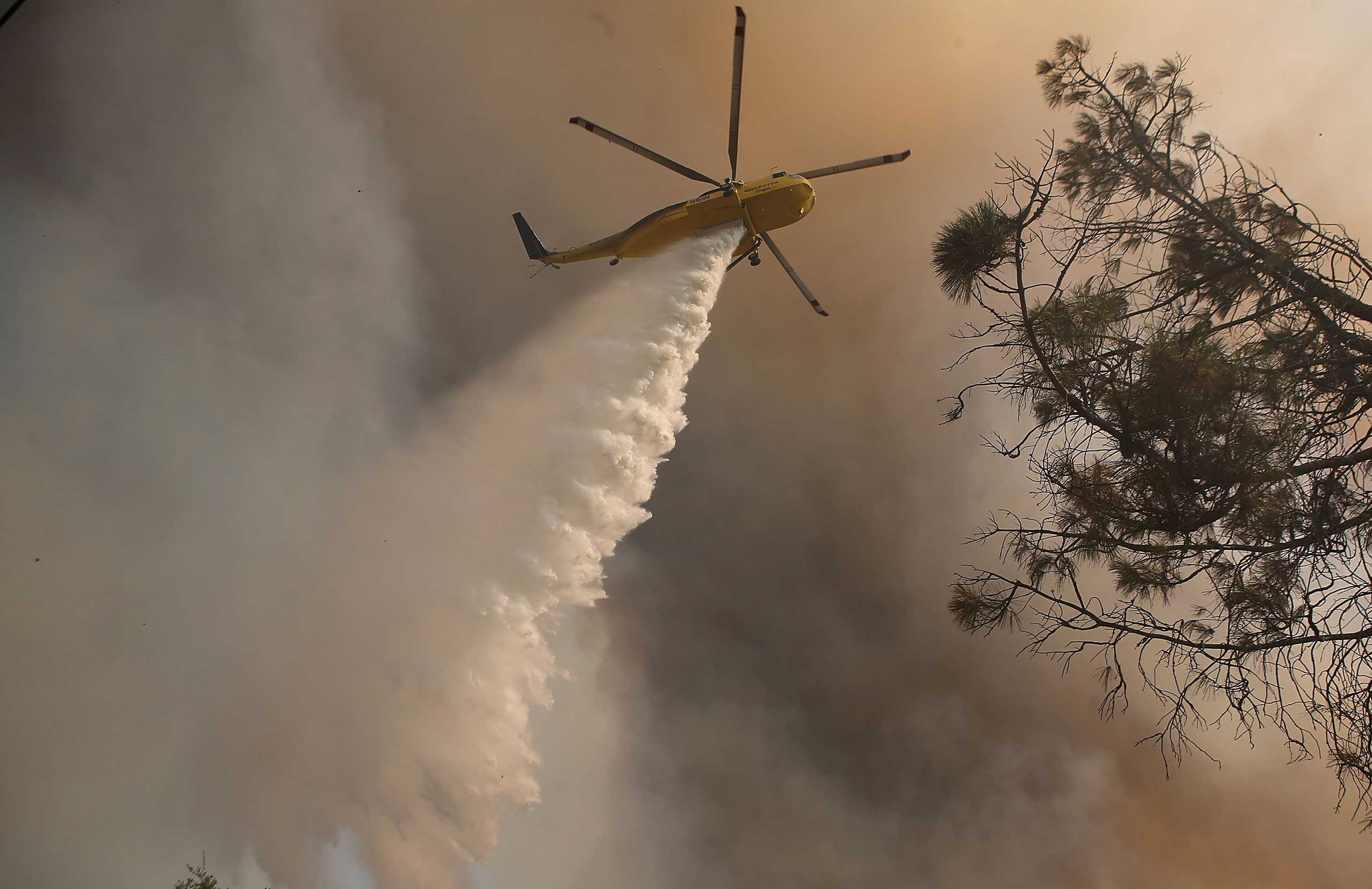 A firefighting helicopter drops water on spot fires while battling the Rocky Fire in Lower Lake, Calif. on July 30, 2015.