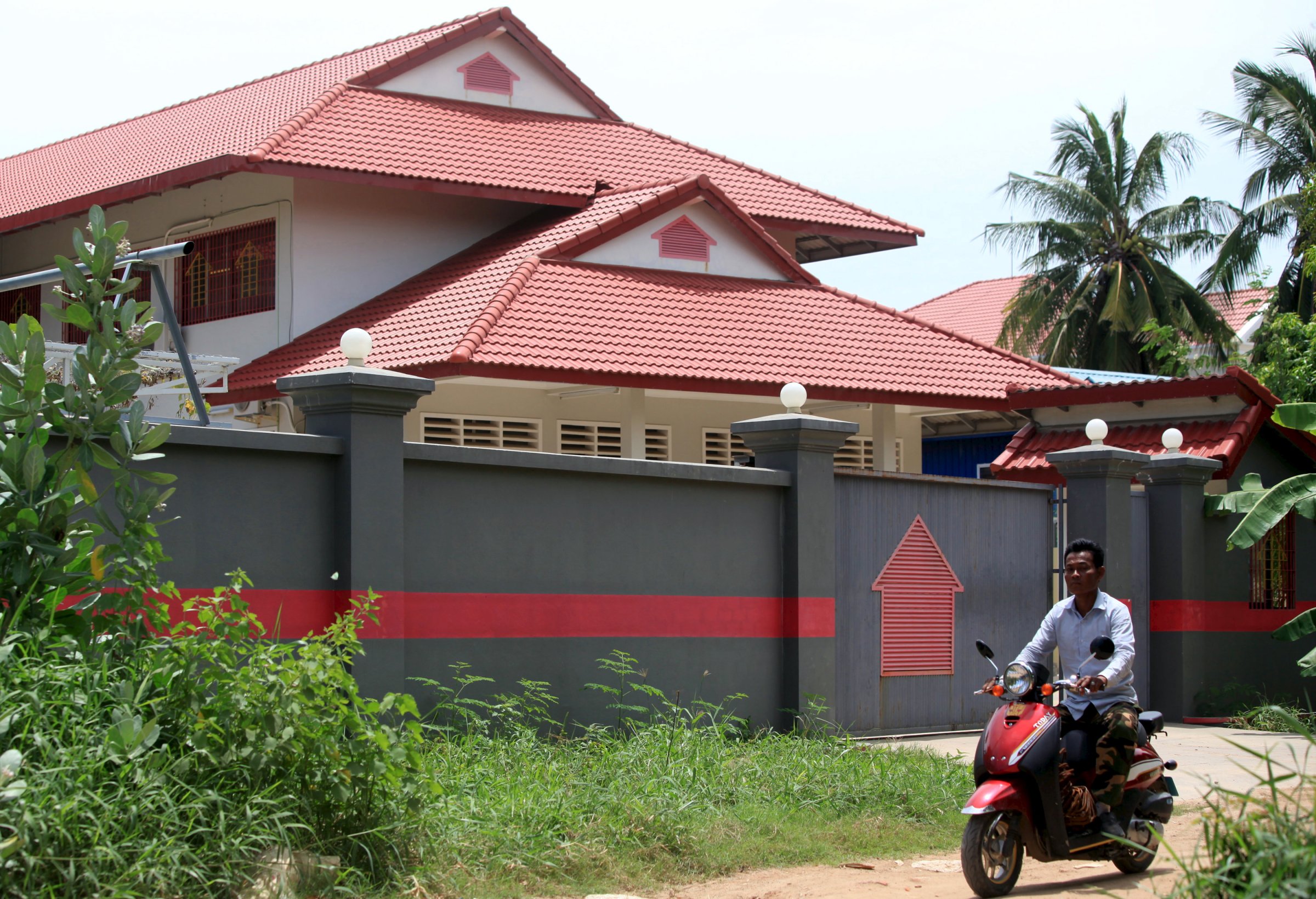 A man rides a motorcycle past a house that is used to temporarily house asylum seekers sent from a South Pacific detention centre, in Phnom Penh, Cambodia August 31, 2015.