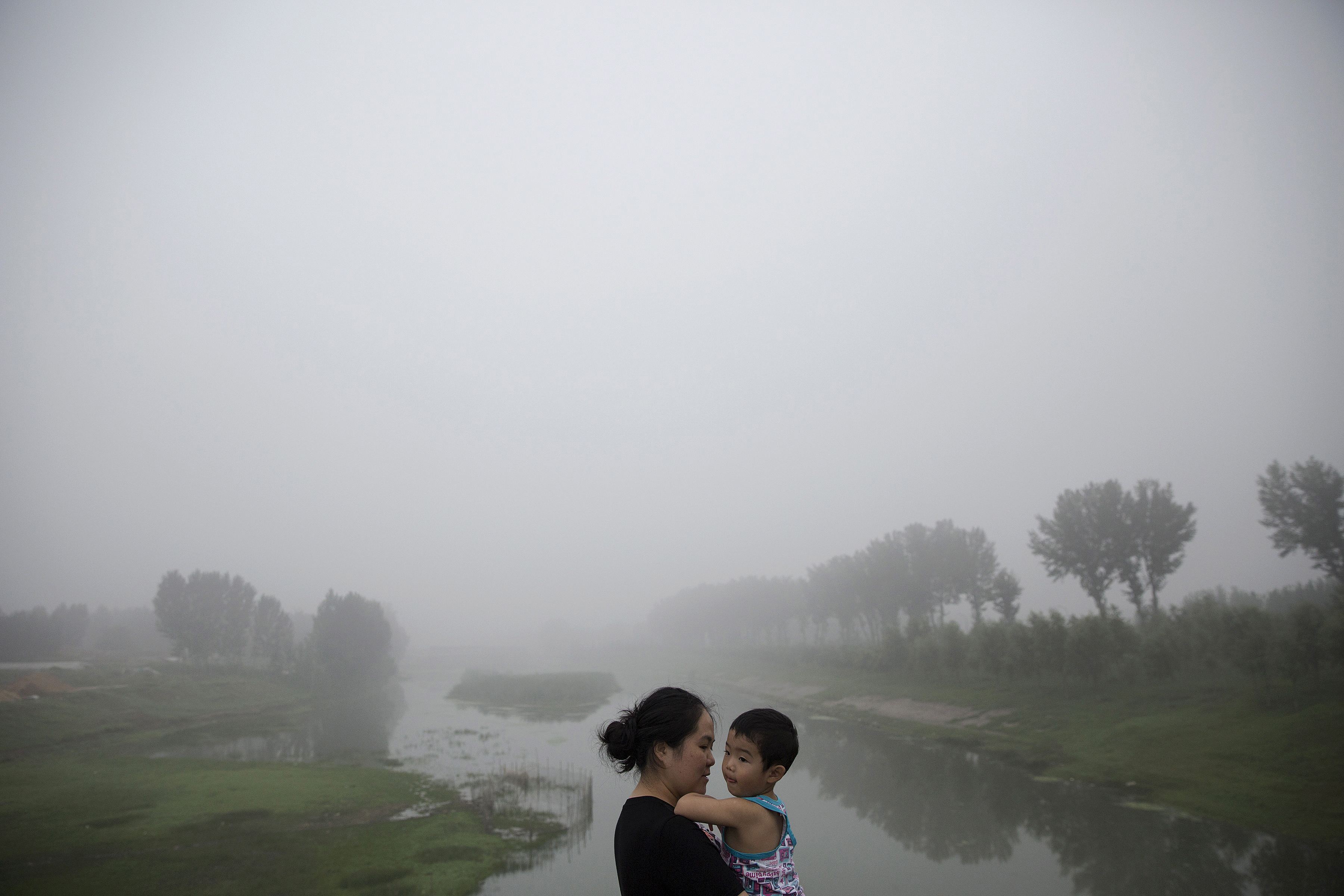 A woman holds a child as travelers wait for the highway from Beijing to China's Hebei Province to reopen after it was closed due to low visibility, on a heavily polluted morning on Aug. 3, 2015. (Damir Sagolj—Reuters)