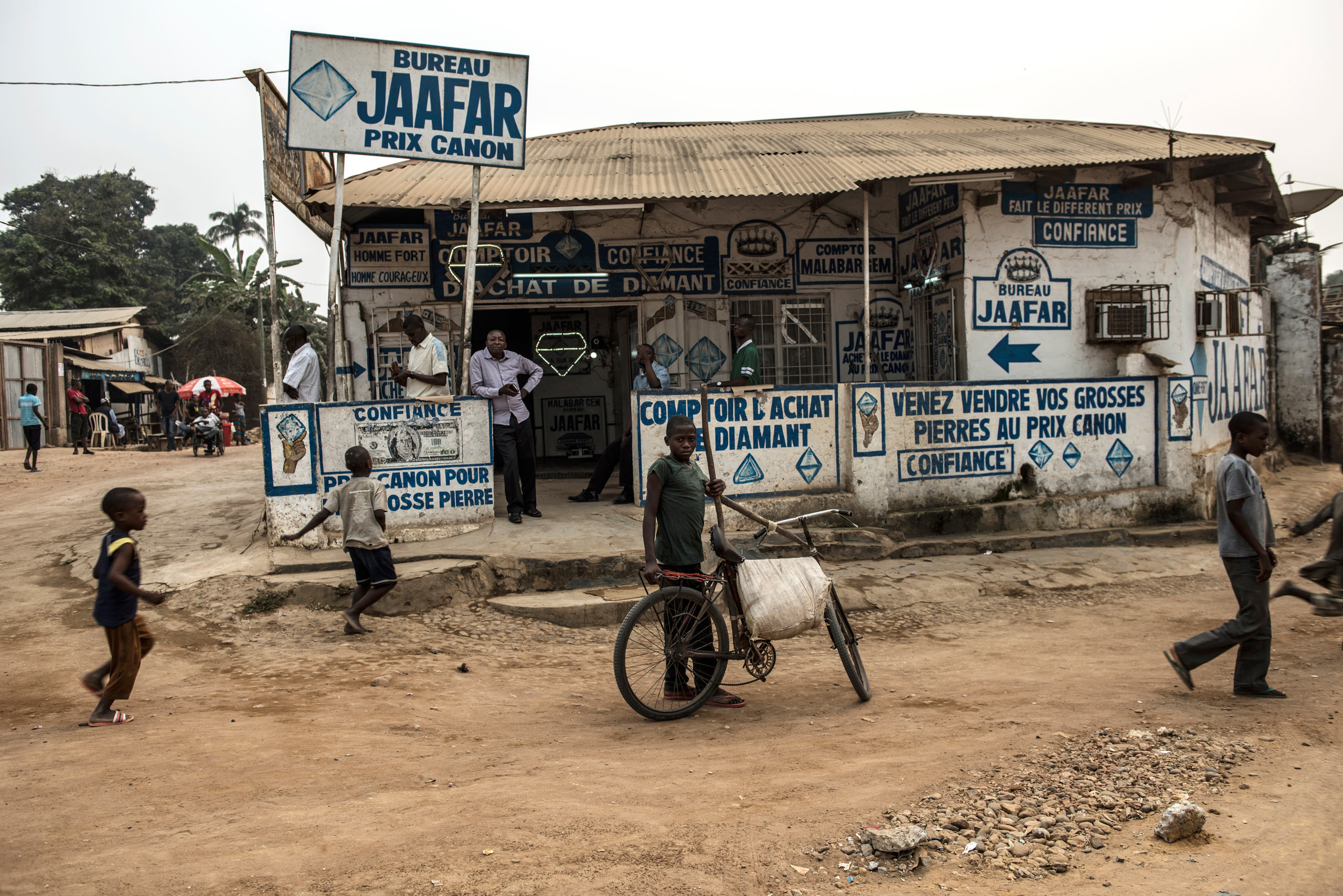 Congolese walk past Jaffar Comptoir, a diamond-trading house, in Tshikapa, Kasaï, Democratic Republic of Congo, Aug. 10, 2015.
