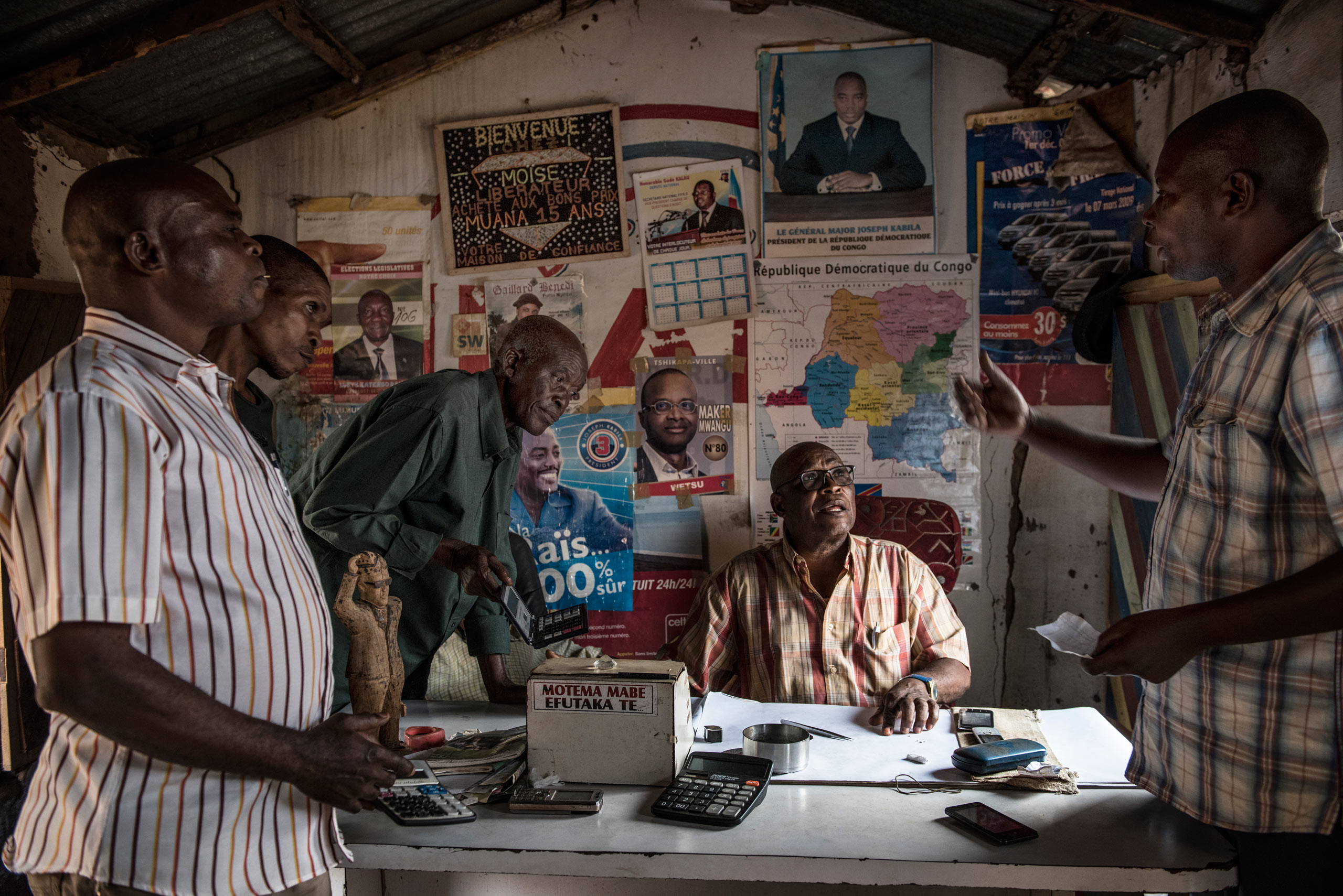 Congolese diamond buyers Daniel Tunuanga, 61, and Kindambay Funji, 69, look over diamonds in the Mwankenza Comptoir, a diamond trading house, in Tshikapa, Kasaï, Democratic Republic of Congo, Aug. 10, 2015. 
                              The sign, in Lingala, reads:  A bad heart (person) doesn't pay.