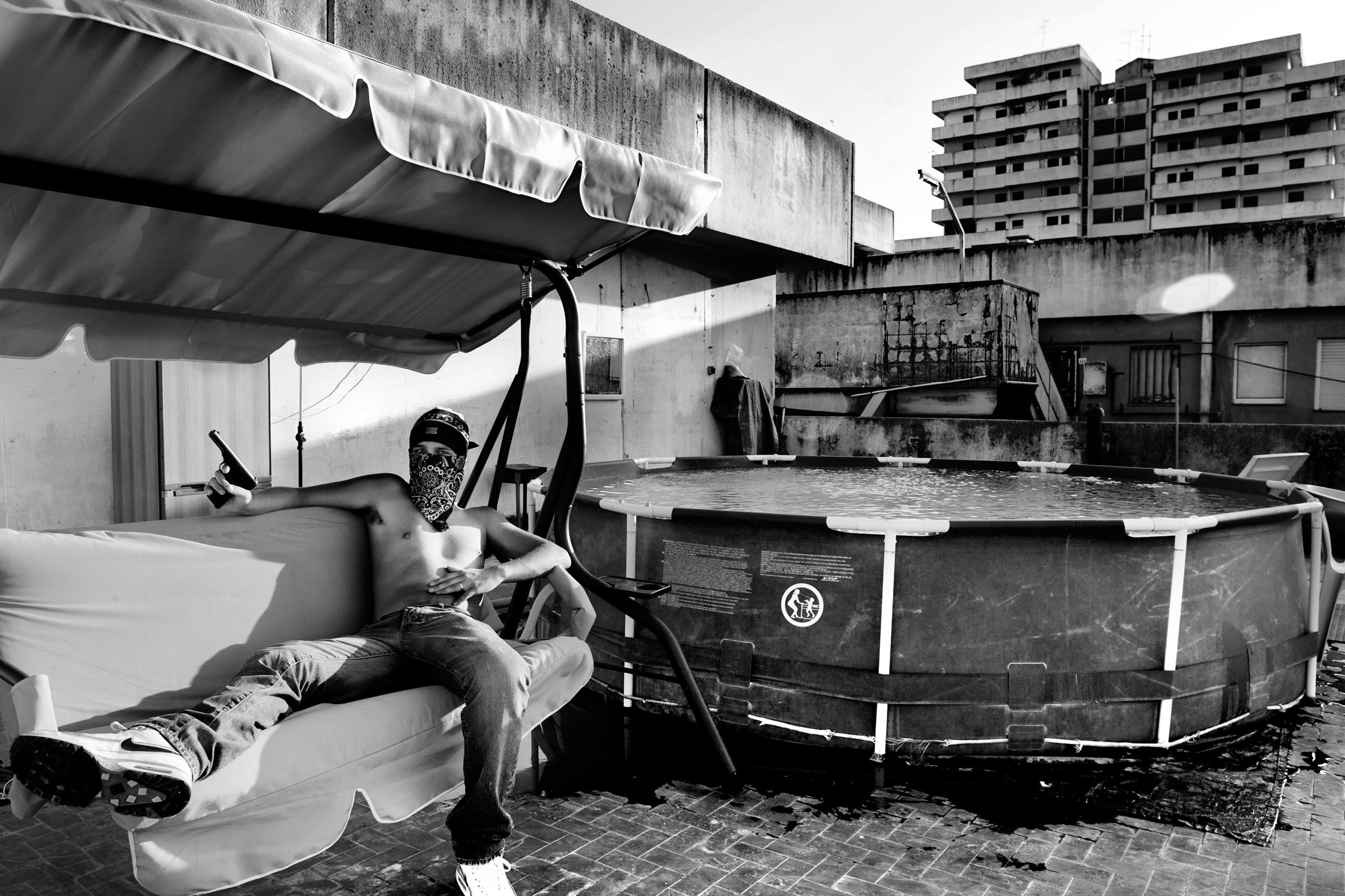 A pusher with his 7,65 gun on the top of  The Sails,  a particular building so called for its shape, in the Scampia neighborhood in Naples.