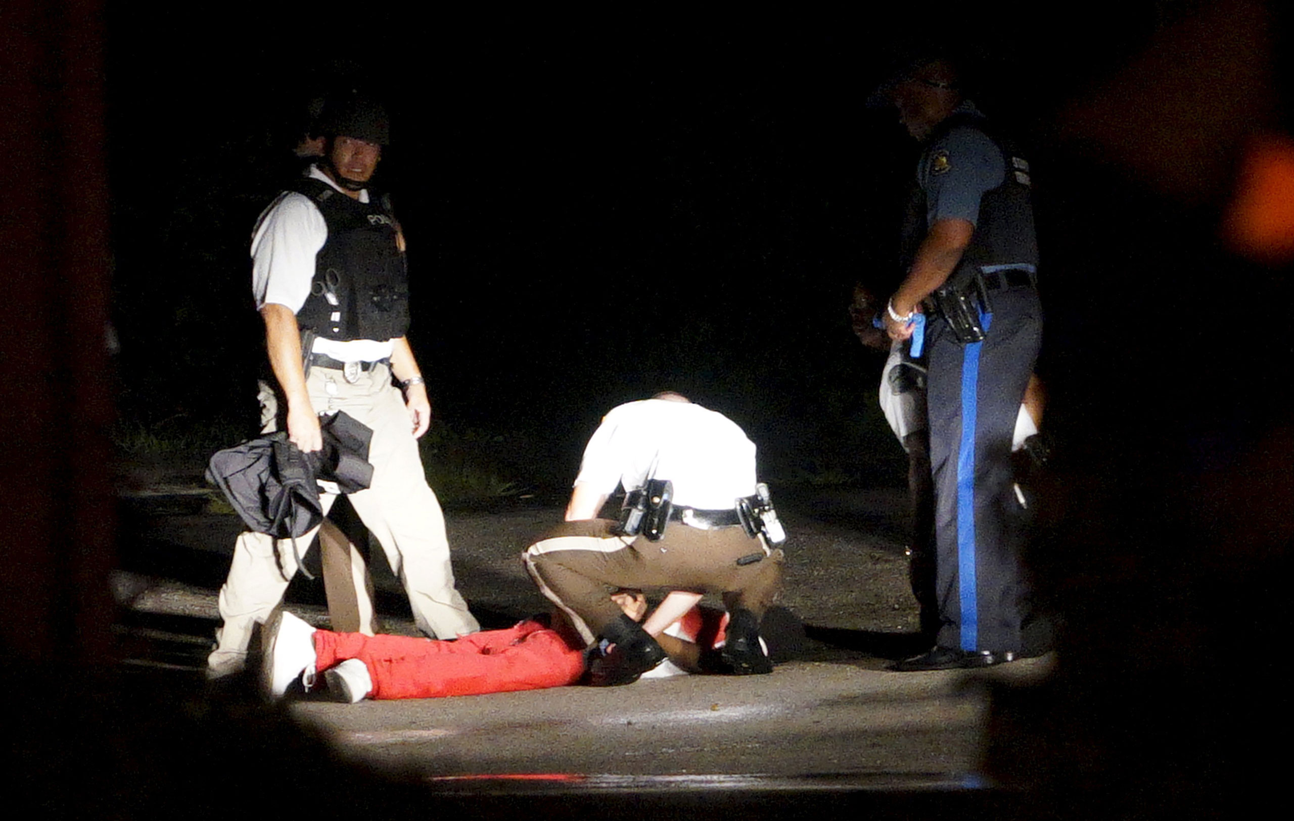 A black man lies badly wounded with blood on his shirt after a police officer involved shooting in Ferguson, Mo., on August 9, 2015.