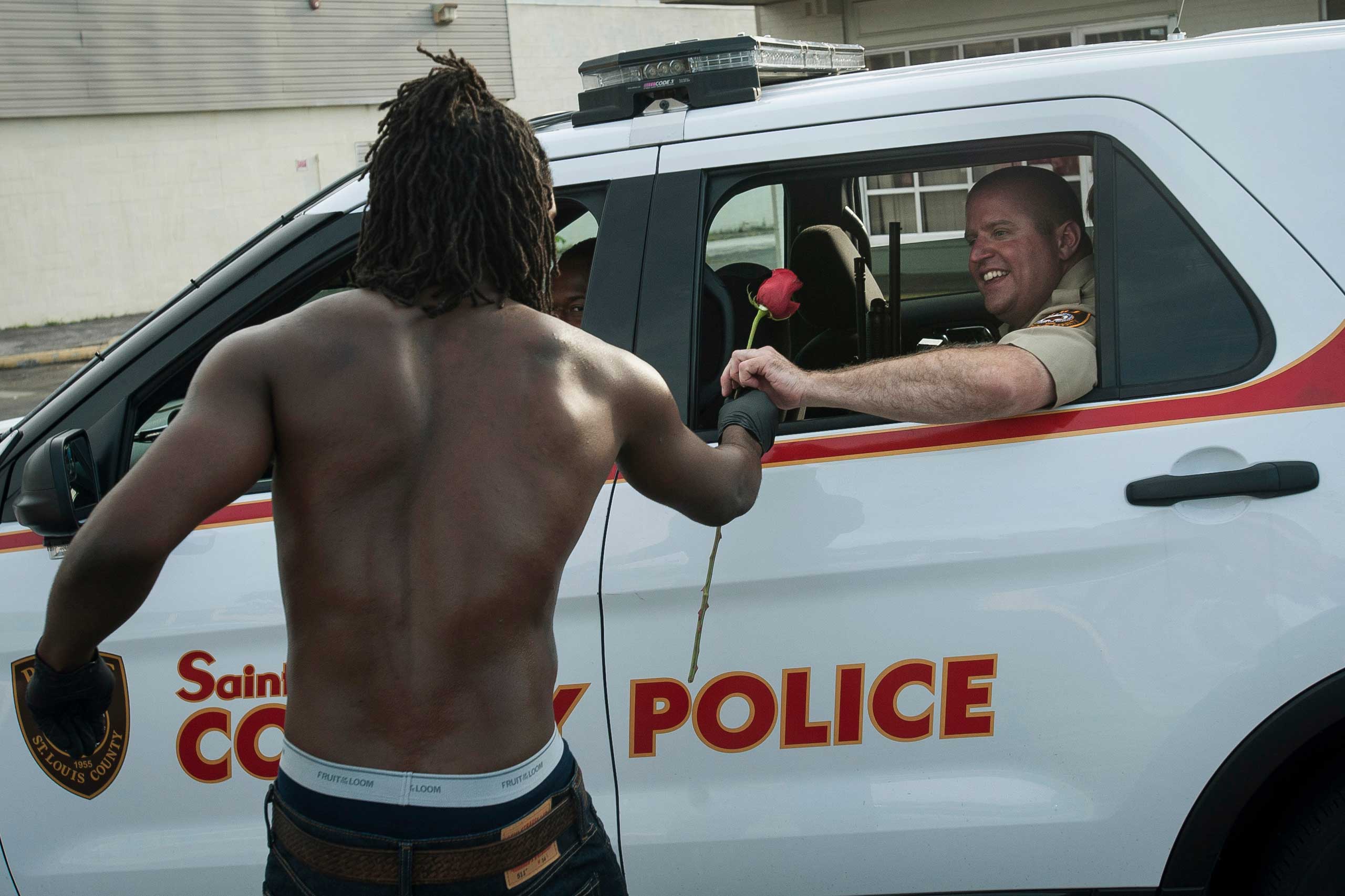 Resident John West hands a rose to a police officer during cleanup efforts in Ferguson, Mo. on Aug. 19, 2014. (Mark Kauzlarich—Reuters)