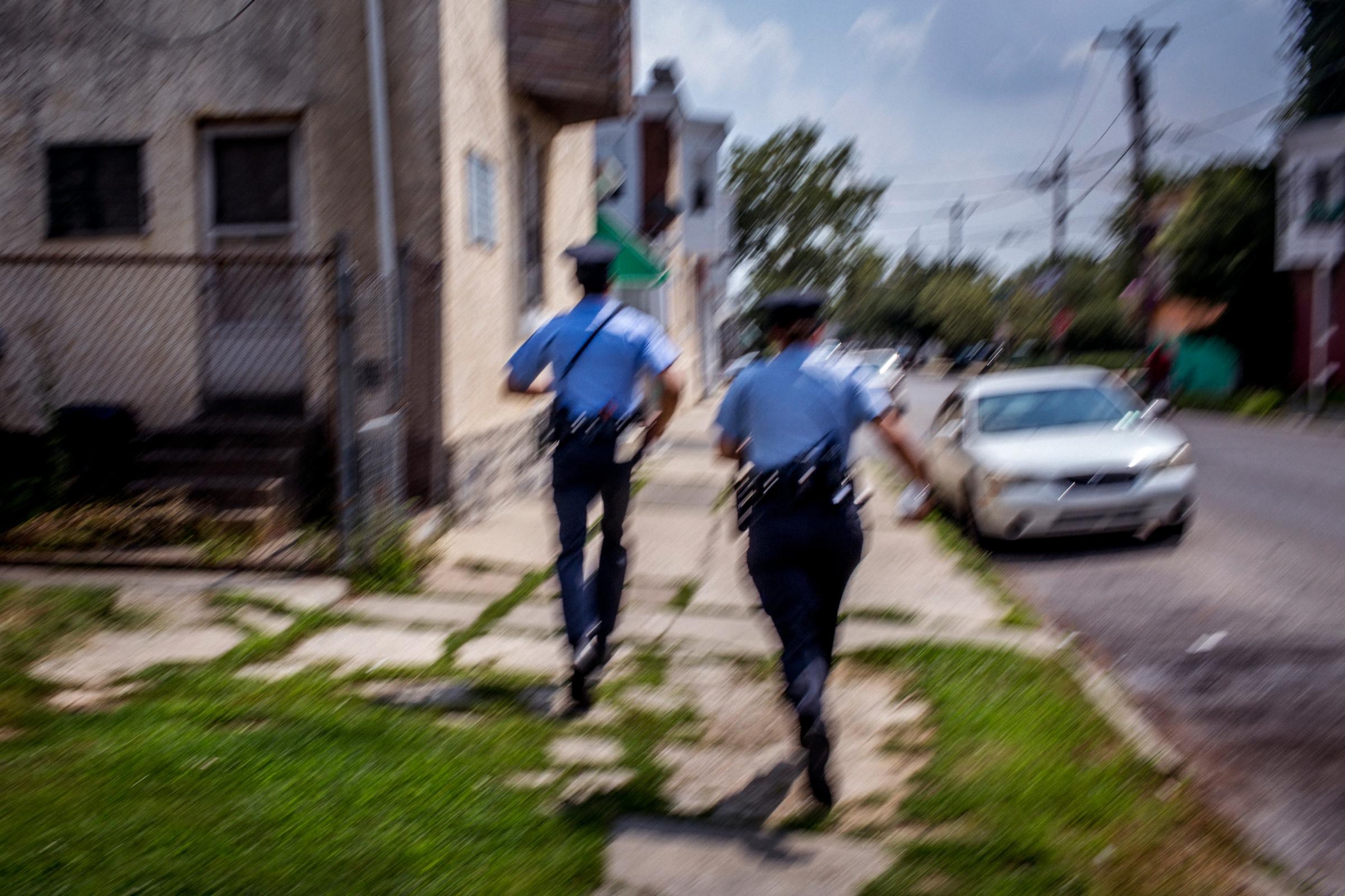 July 28th, 2015. Philadelphia, PA. First year "foot beat" officers Jonathan Dedos (left) and Ashley Sipos (right) run down the street in West Philadelphia after a radio call comes in that someone has been shot in a nearby housing complex.(Natalie Keyssar)