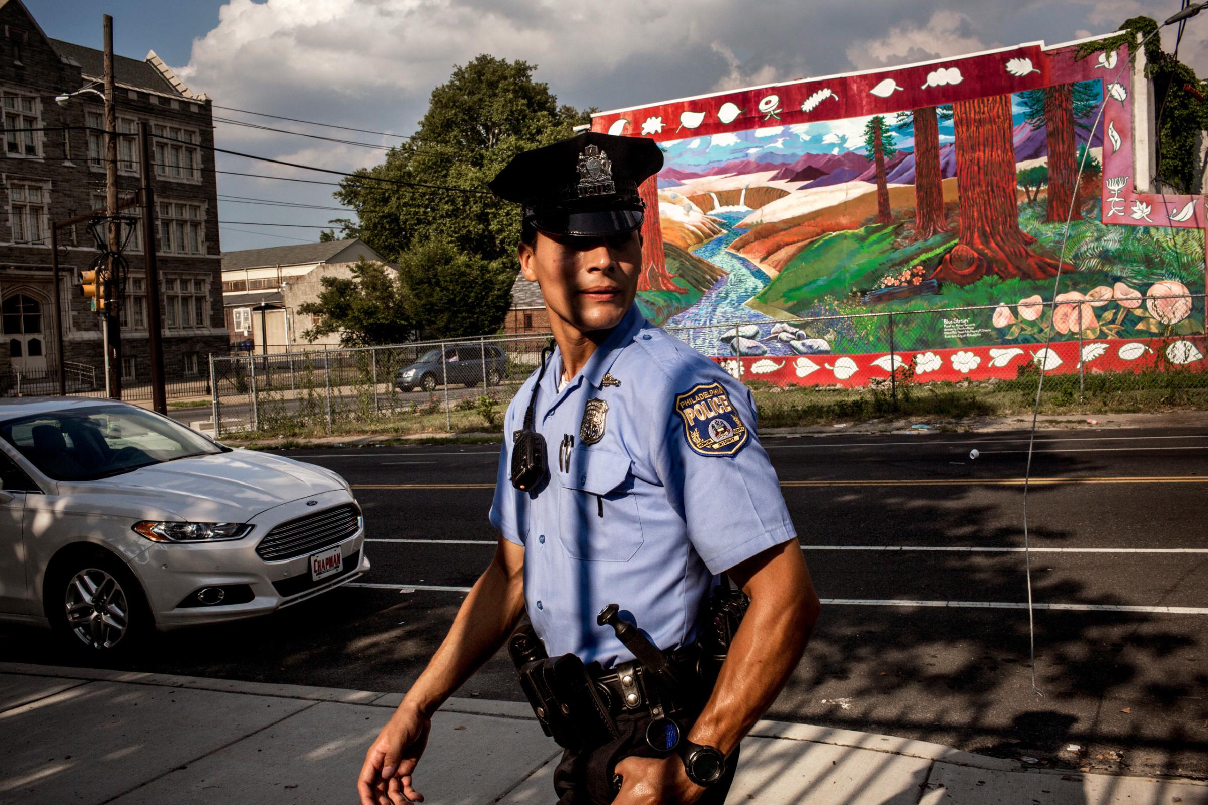 July 28th, 2015. Philadelphia, PA. First year officer Jonathan Dedos (a "foot beat") walks his beat, searching for a shooting suspect. (Natalie Keyssar)