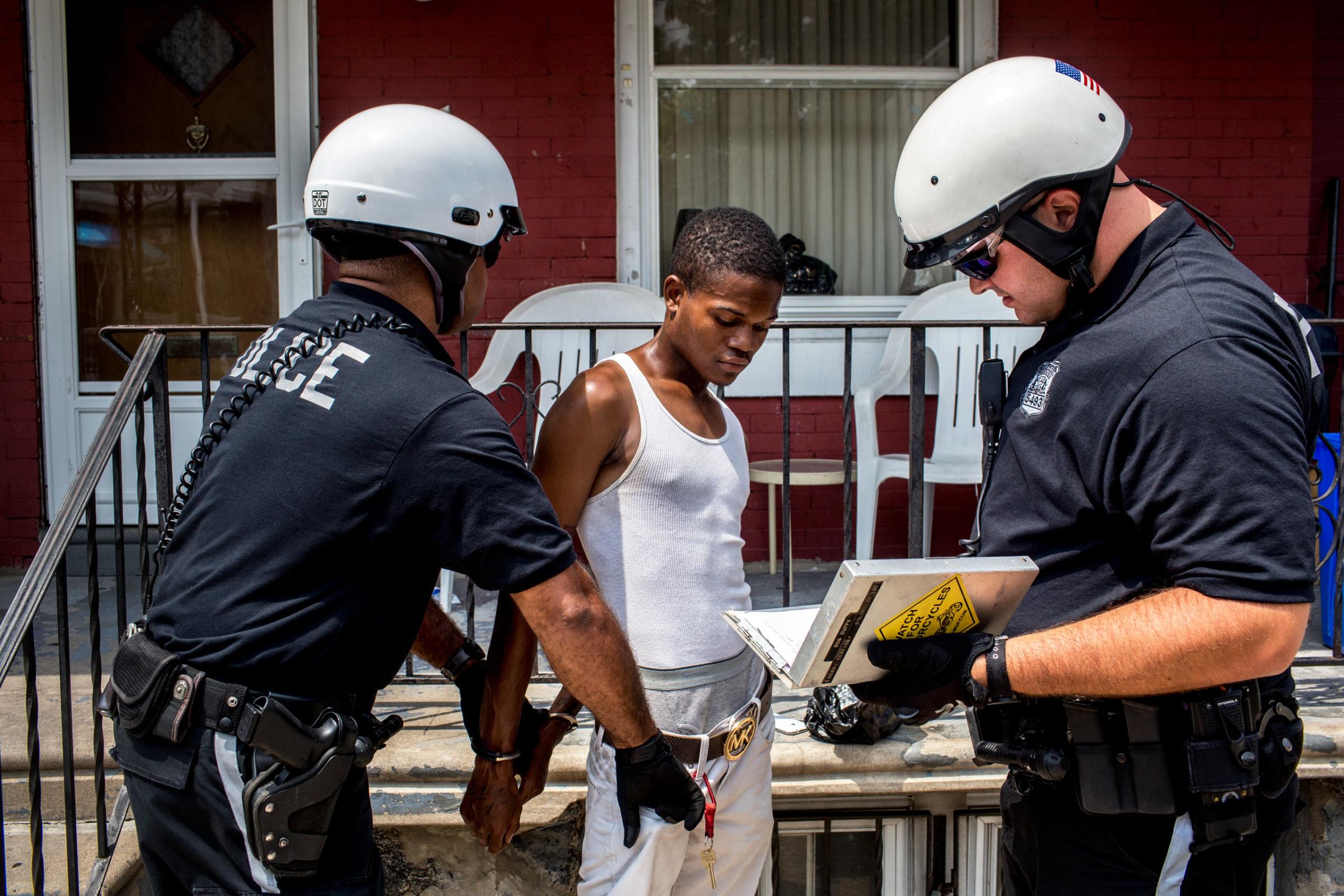 July 29, 2015. Philadelphia, PA. Officers Brian Dillard (left) and Robert Saccone (Right) detain a young man who fit the description of a criminal suspect in West Philadelphia. After being searched and questioned he was released. (Natalie Keyssar)