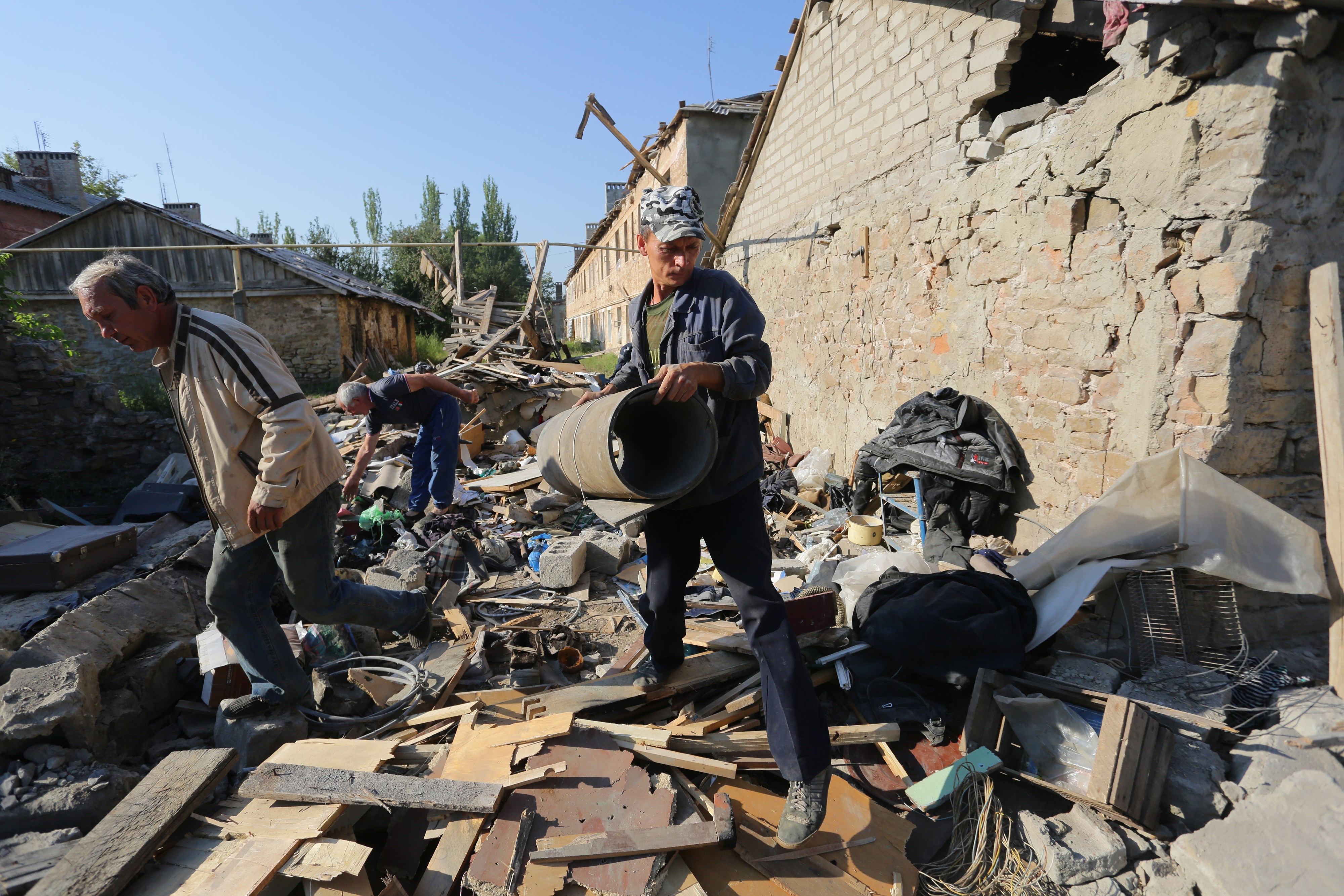 Residents clean up the debris of their destroyed house after shelling between Ukrainian forces and pro-Russian separatists on August 10, 2015 in Golmovsky village, Donetsk region. (Aleksey Filippov—AFP/Getty Images)