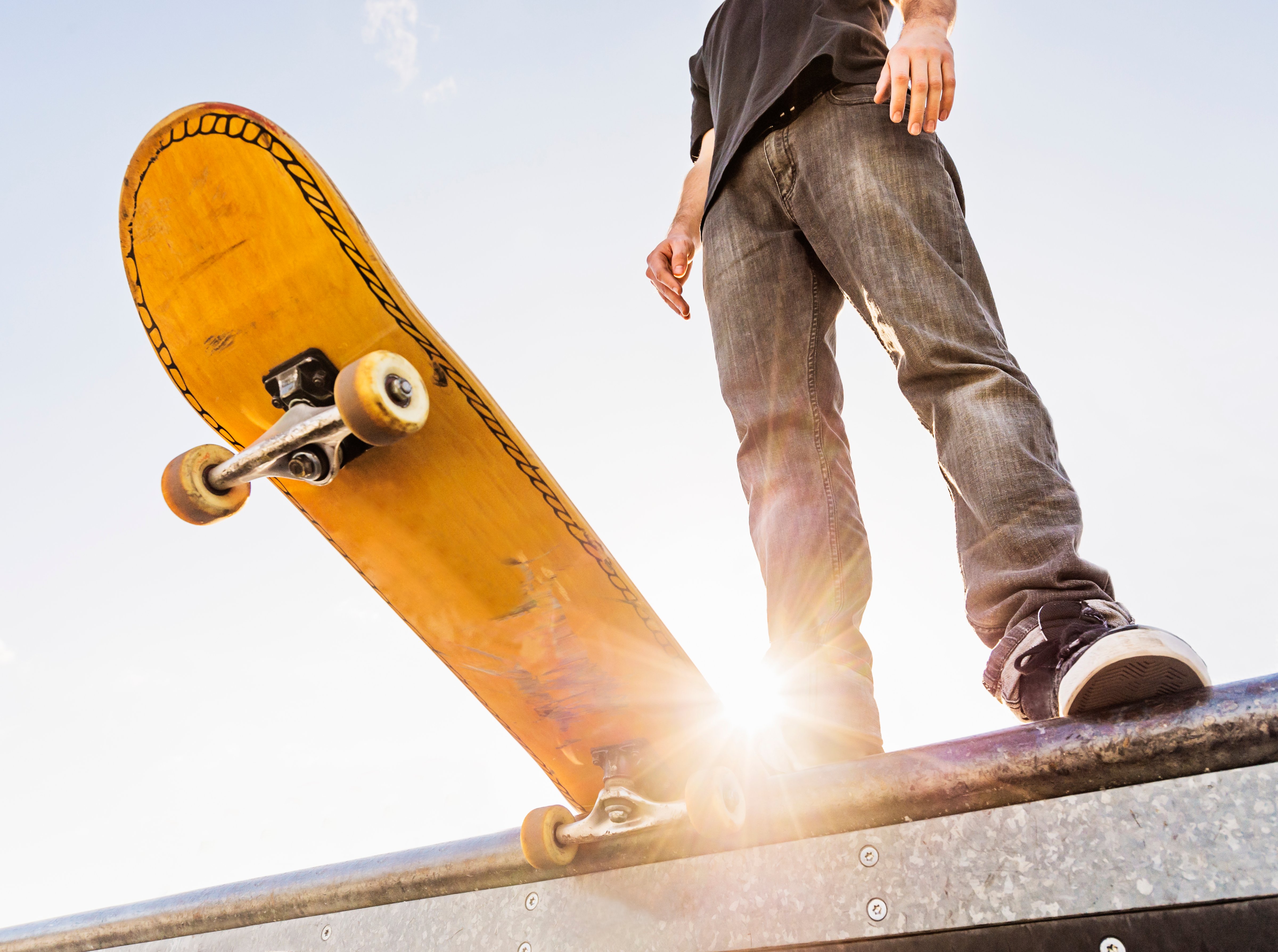 Man with skateboard at the edge of ramp (Daniel Grill—Getty Images/Tetra images RF)