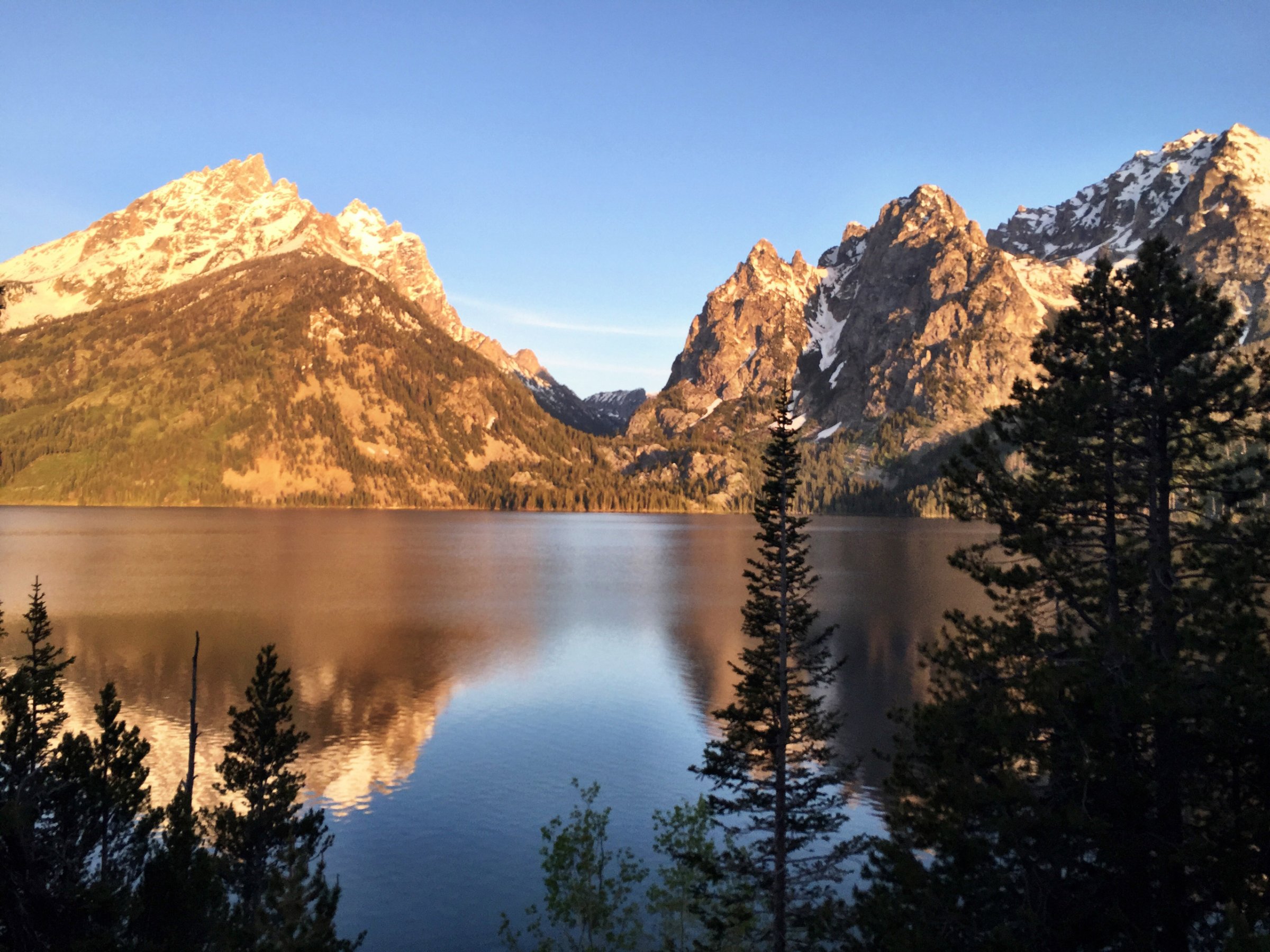Alpenglow shining on the Grand Tetons is reflected in Jenny Lake June 4, 2015, in Grand Teton National Park, Wyoming. The park offers amazing scenery and hiking opportunities without the crowds of nearby Yellowstone National Park. (Erin Madison/Great Falls Tribune via AP) MANDATORY CREDIT