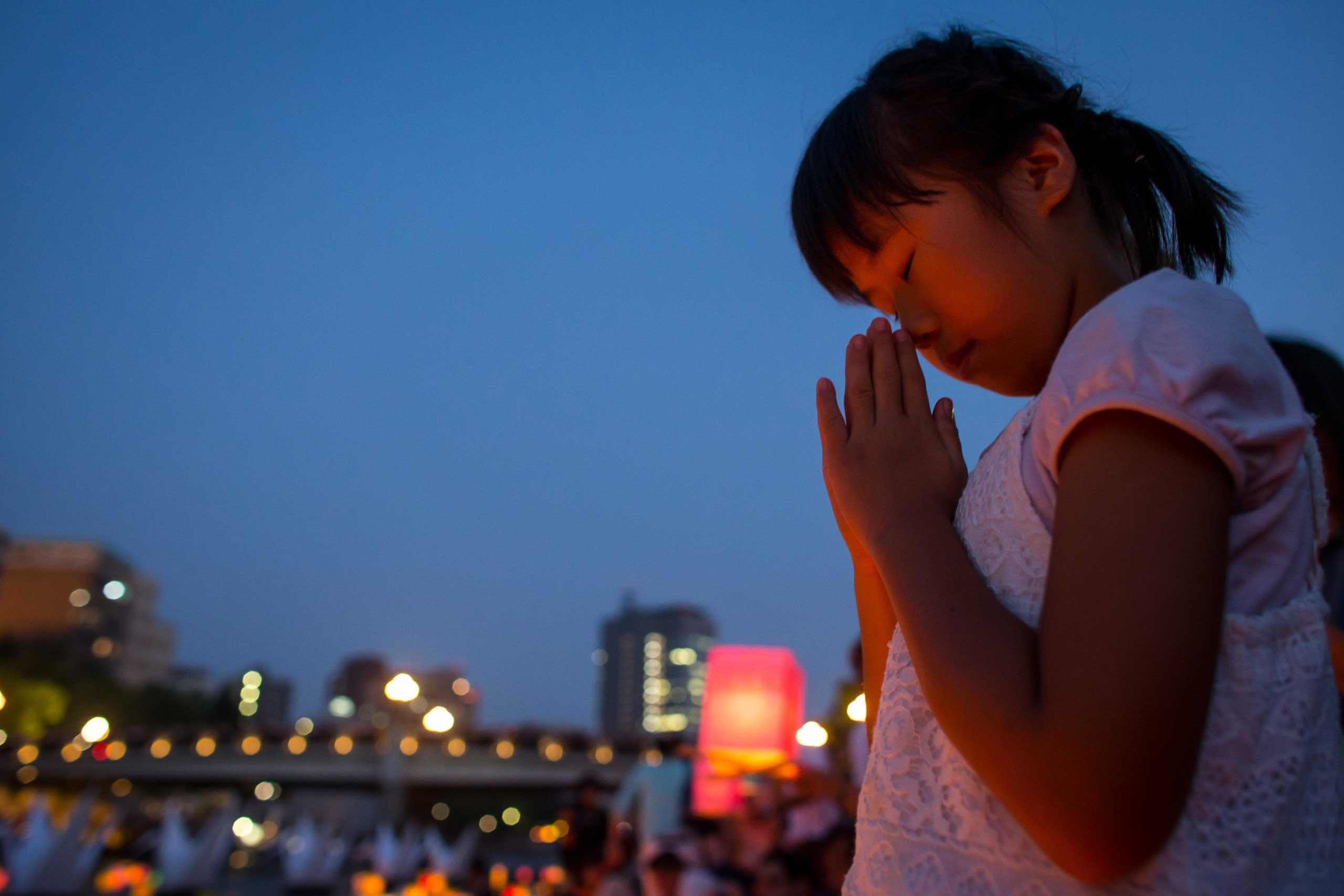 A young girl prays after floating a candle lit paper lantern on the river during 70th anniversary activities, comemorating the atomic bombing of Hiroshima at the Hiroshima Peace Memorial Park, on Aug. 6, 2015