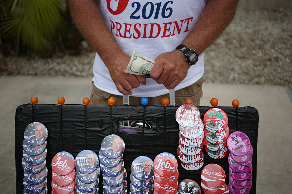 A vendor holds money while selling buttons and t-shirts outside an event where Former Governor of Florida Jeb Bush announced he will seek the 2016 Republican presidential nomination on the Kendall Campus of Miami Dade College in Miami, Florida, U.S., on Monday, June 15, 2015. In an attempt to follow his brother and father into the nation's highest office, Bush announced today that he's running for president of the United States. Photographer: Luke Sharrett/Bloomberg via Getty Images