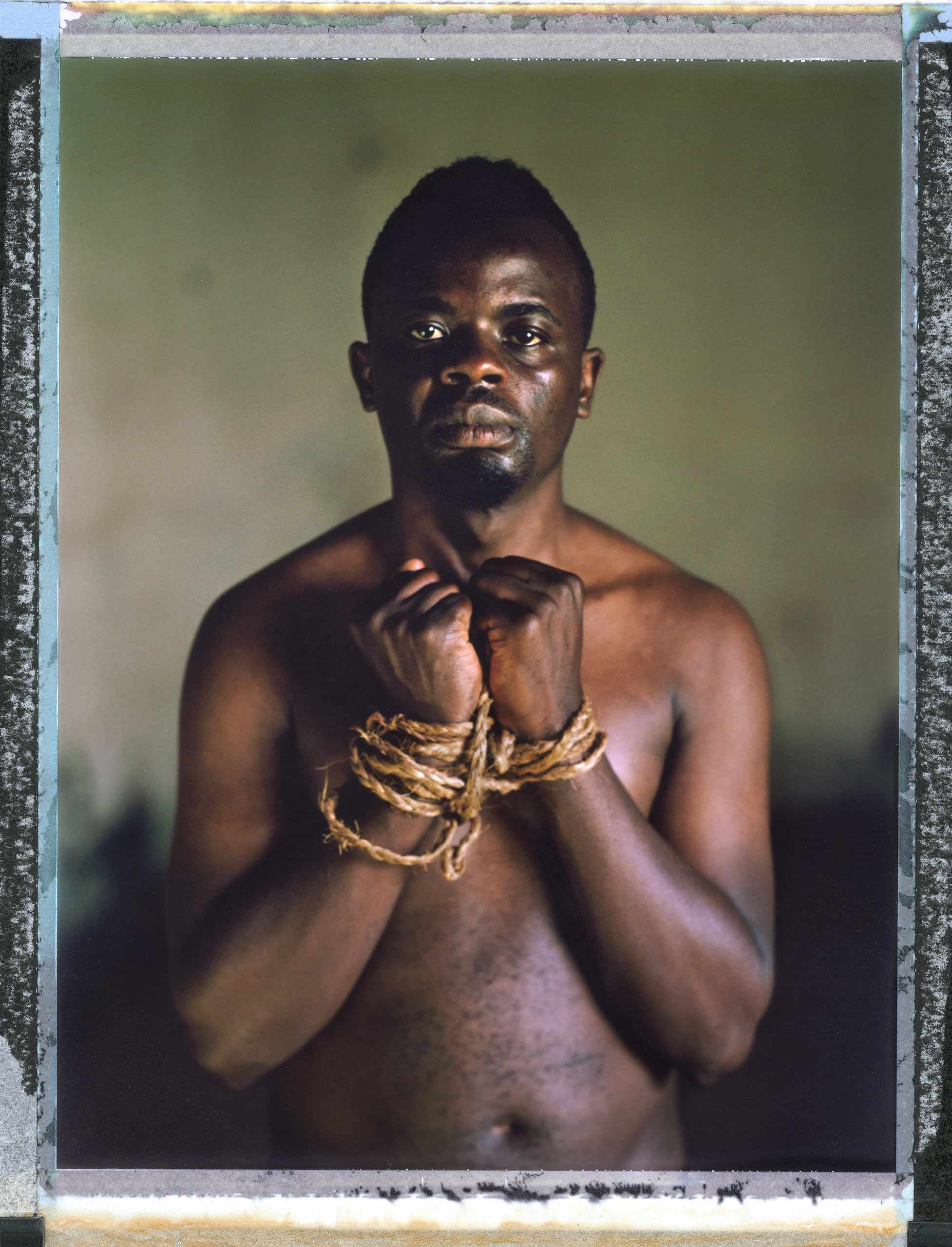 A posed portrait of 26 year old Kamarah Apollo, a gay activist in Uganda. Apollo lists the discrimination he has faced: “In 2010 I was chased from school when they found out that I was in relationship with fellow male student. I was also disowned by my family because of my sex orientation. I left home with no option but to join sex work for survival and fight for our gay and sex workers’ rights because I was working on streets. I was also arrested several times because police officers thought I was promoting homosexual acts in Uganda. I have been tortured several times by homophobic people and police officers by tying me with ropes and being beaten, pierced by soft pins, nicknamed, a lot of psychological torture by local leaders and police. I can’t forget when I was raped in the police cell by prisoners, after all that I decided to start an organization with some campus students. An msm organization called kampuss liberty Uganda. During the petitioning of the anti-homosexuality act I appeared on local televisions so much and it became hard to me to a permanent place to stay because the majorities are homophobic. I also appeared in local newspapers as a promoter of homosexuals so right now it’s hard for me to get a safe place to rent yet I am not working. I was fired from work because I am gay.” Uganda, September 2014.  While many countries around the world are legally recognizing same-sex relationships, individuals in nearly 80 countries face criminal sanctions for private consensual relations with another adult of the same sex. Violence and discrimination based on sexual orientation or gender expression is even more widespread. Africa is becoming the worst continent for Lesbian, Gay, Bi-sexual, Transgender, Queer, Inter-sex (LGBTQI) individuals. More than two thirds of African countries have laws criminalizing consensual same-sex acts. In some, homosexuality is punishable by death. In Nigeria new homophobic laws introduced in 2013 led to dramatic increase