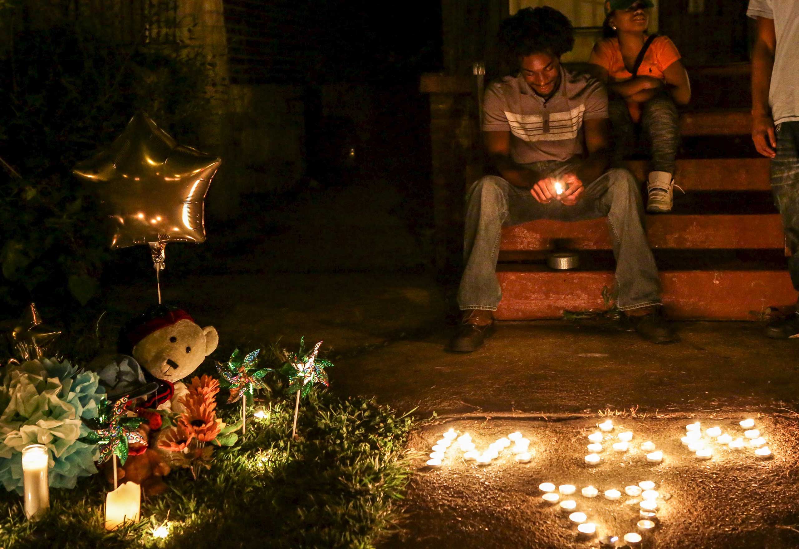 Chris Ball-Bey, the brother of Mansur Ball-Bey, sits by his brother's memorial after a candlelight vigil on Walton Ave in St. Louis, Mo., on Aug. 20, 2015. (Lawrence Bryant—Reuters)