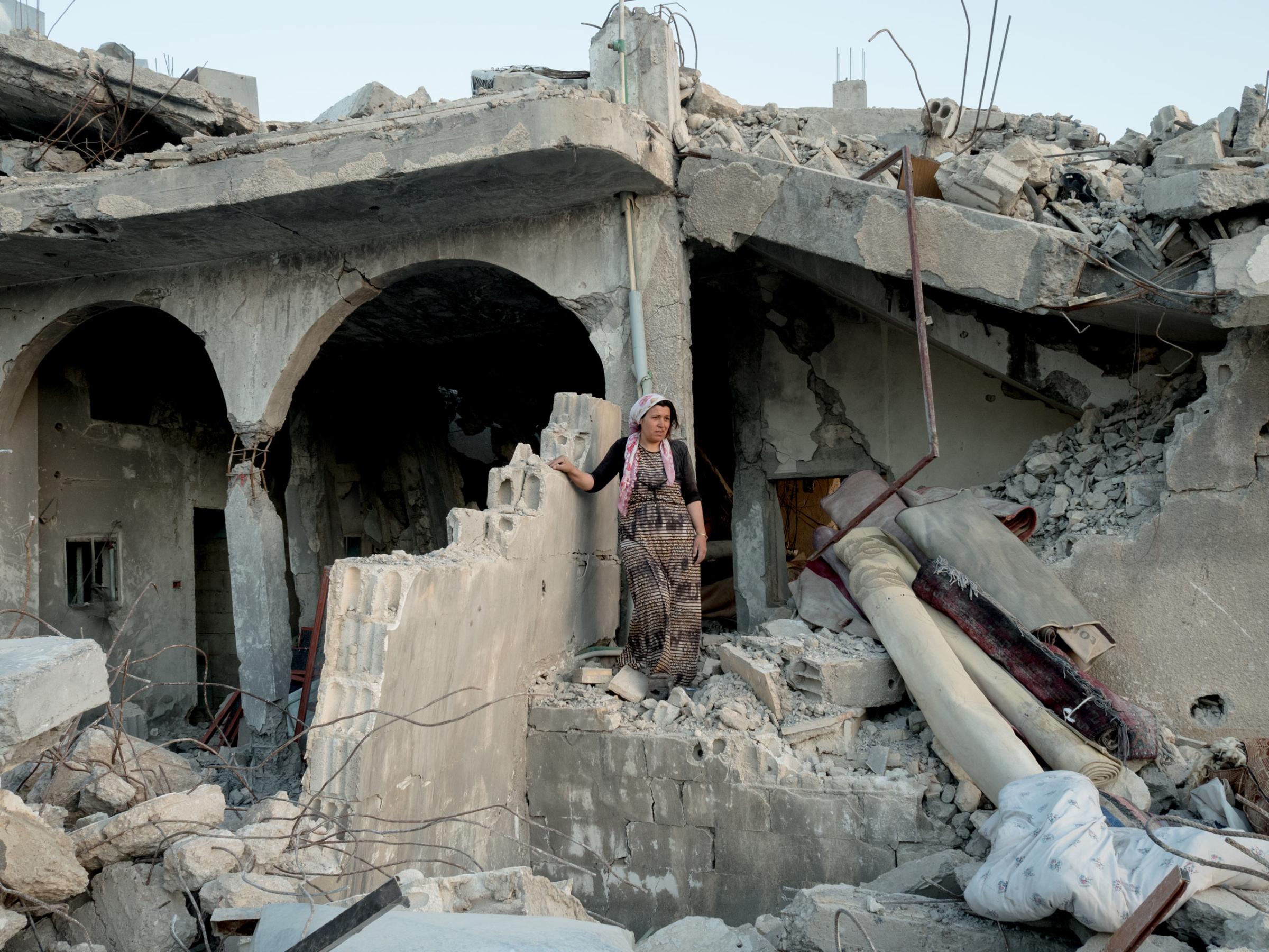 SYRIA. Kobani / Kobane (Arabic: Ayn al Arab) . 06 August 2015. A woman walking on the rubble of her house.