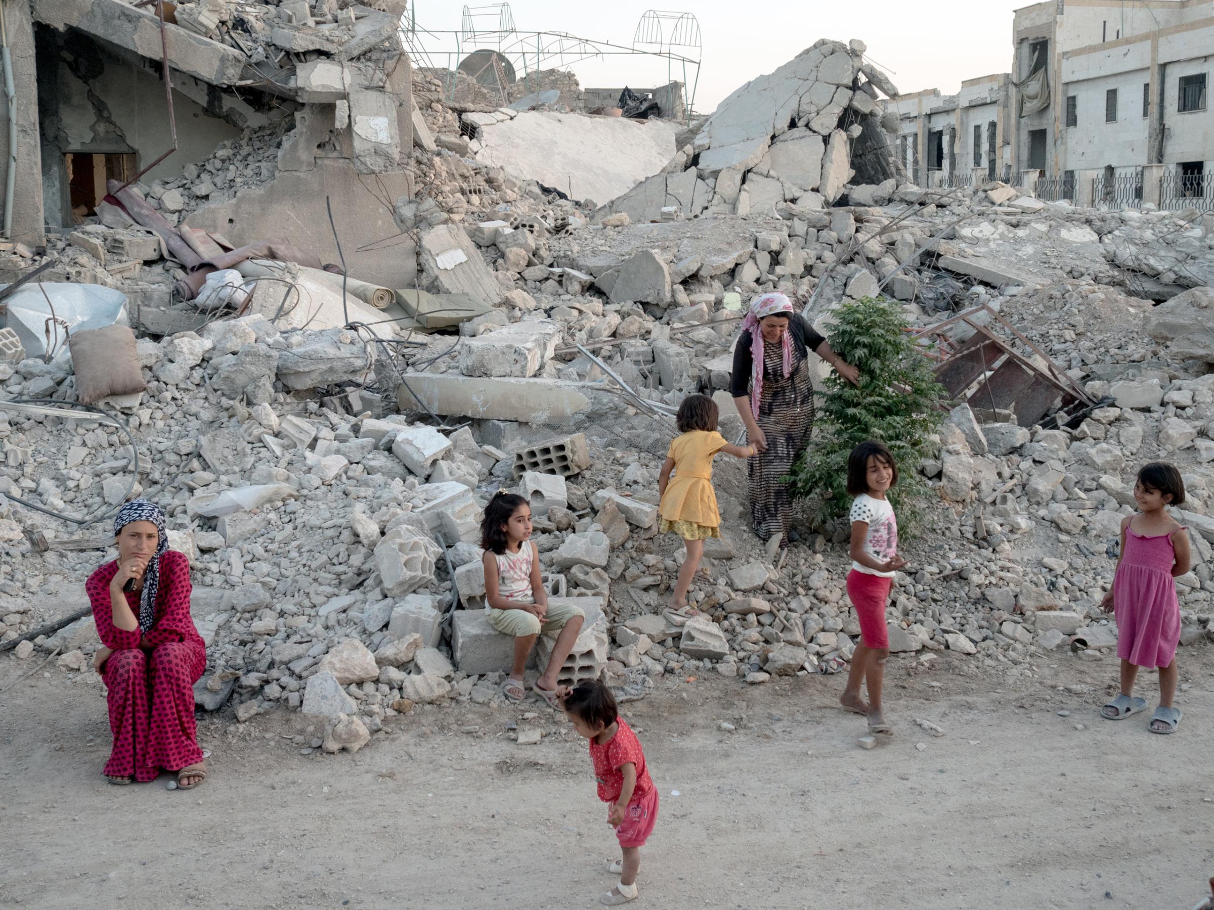 SYRIA. Kobani / Kobane (Arabic: Ayn al Arab) . 06 August 2015. A family stands on what is left of their home.