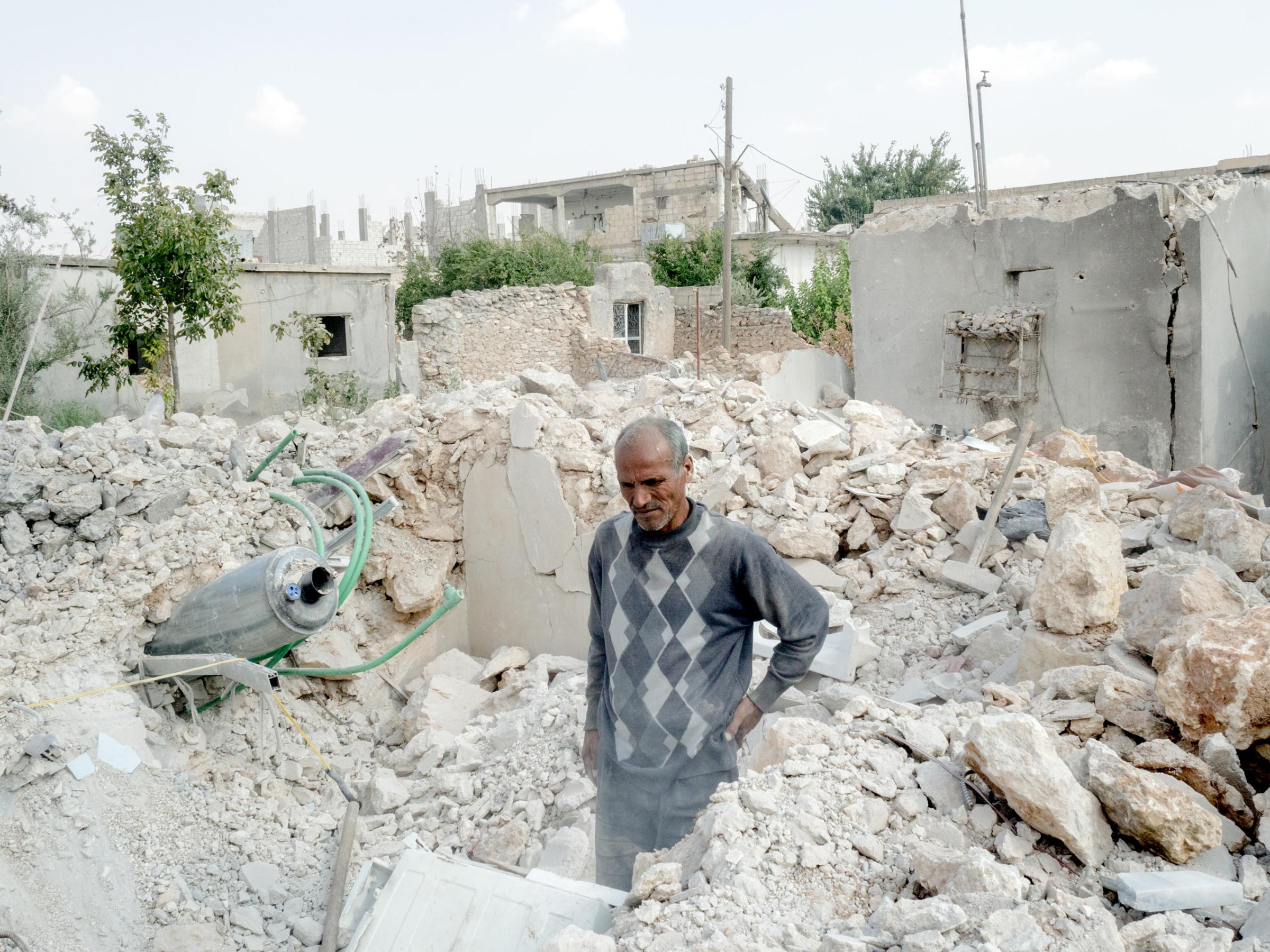 SYRIA. Kobani / Kobane (Arabic: Ayn al Arab) . 07 August 2015. A man is seen trying to recover objects between the rubble of his home.