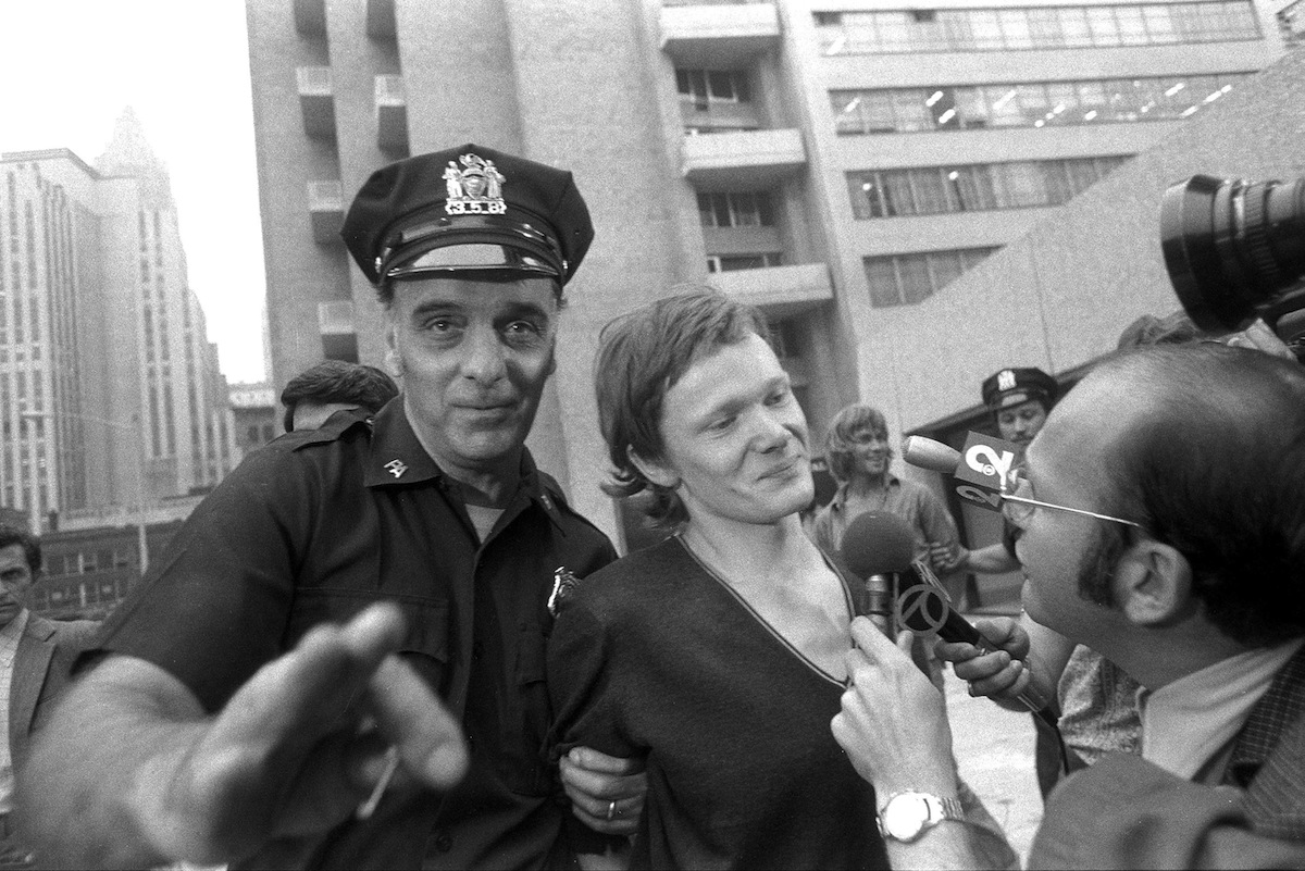 Philippe Petit (center) answers reporter's questions on Aug. 7, 1974, as he is escorted from Beekman Hospital by Port Authority police officer in New York City. Petit was arrested after he walked a tightrope between the two towers of the World Trade Center. (New York Daily News Archive / Getty Images)