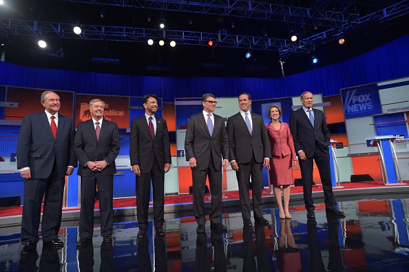 Republican presidential hopefuls (L-R) Jim Gilmore, Lindsey Graham, Bobby Jindal, Rick Perry, Rick Santorum, Carly Fiorina and George Pataki arrive on stage for the start of the Republican presidential primary debate on August 6, 2015 at the Quicken Loans Arena in Cleveland, Ohio.