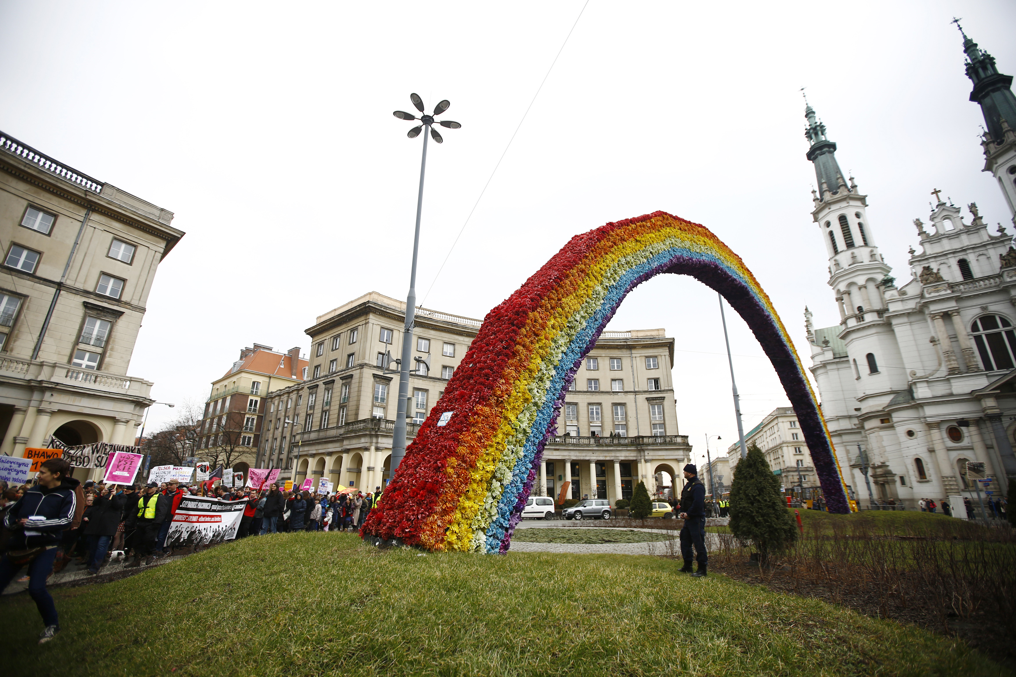 Participants march in front of artistic installation "Rainbow" during an International Woman's Day rally in Warsaw