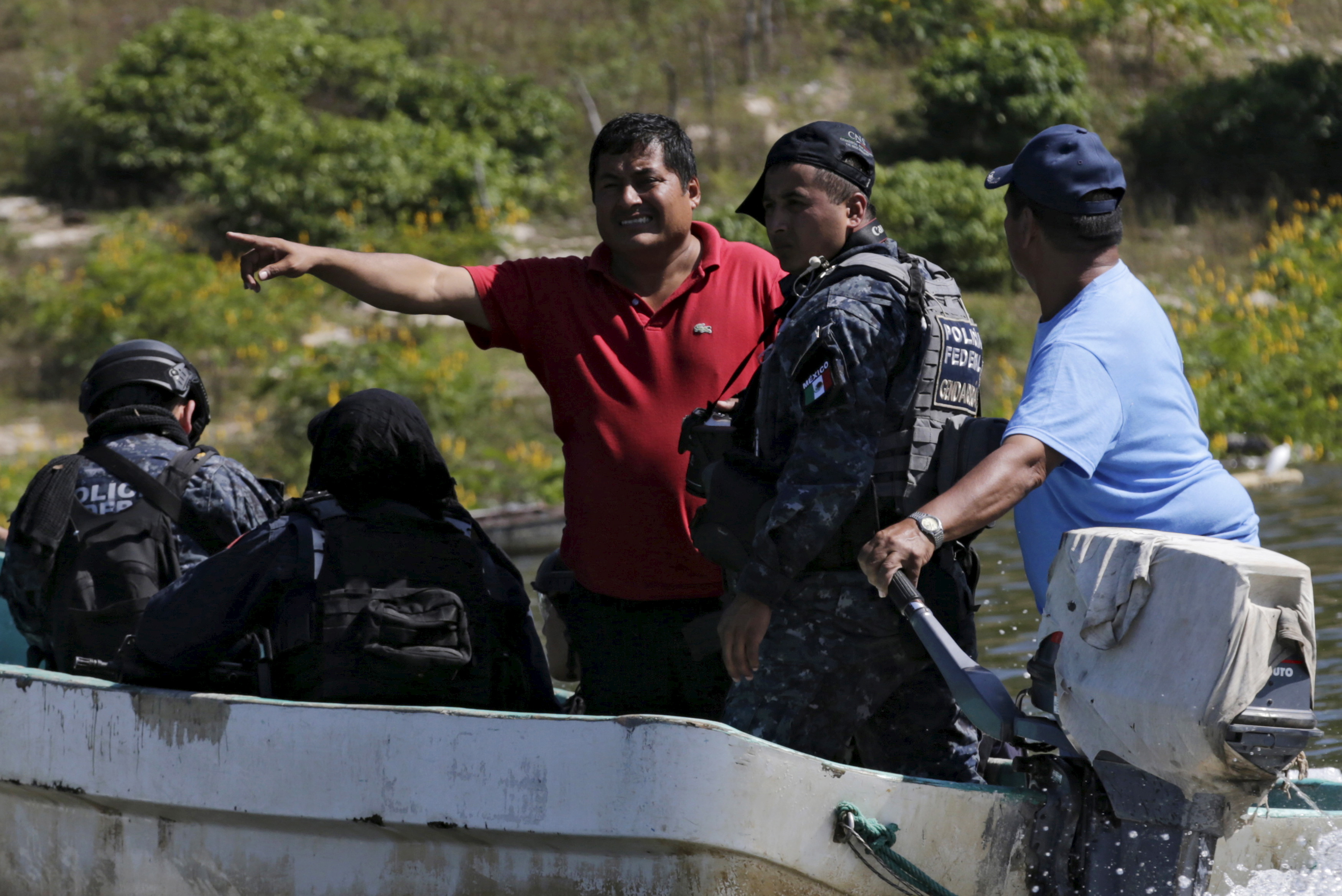 Miguel Angel Jimenez (in red), leader of the community police of Guerrero State (UPOEG), speaks with a federal police on a boat as they seek for the 43 Ayotzinapa students' missing, in Acatlan,  Guerrero, on October 30, 2014. (Henry Romero—Reuters)